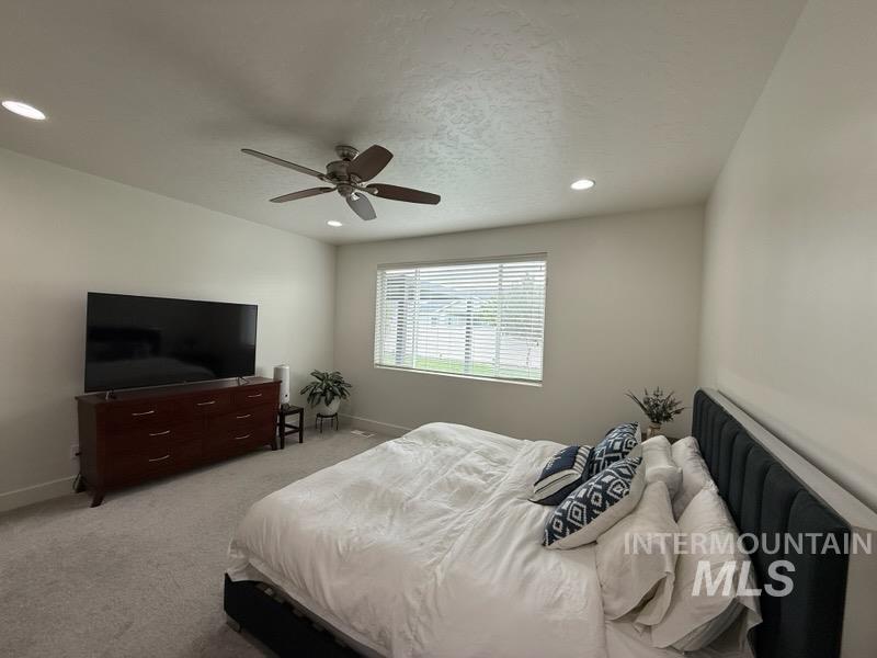 Bedroom with light colored carpet, a ceiling fan, recessed lighting, and a textured ceiling