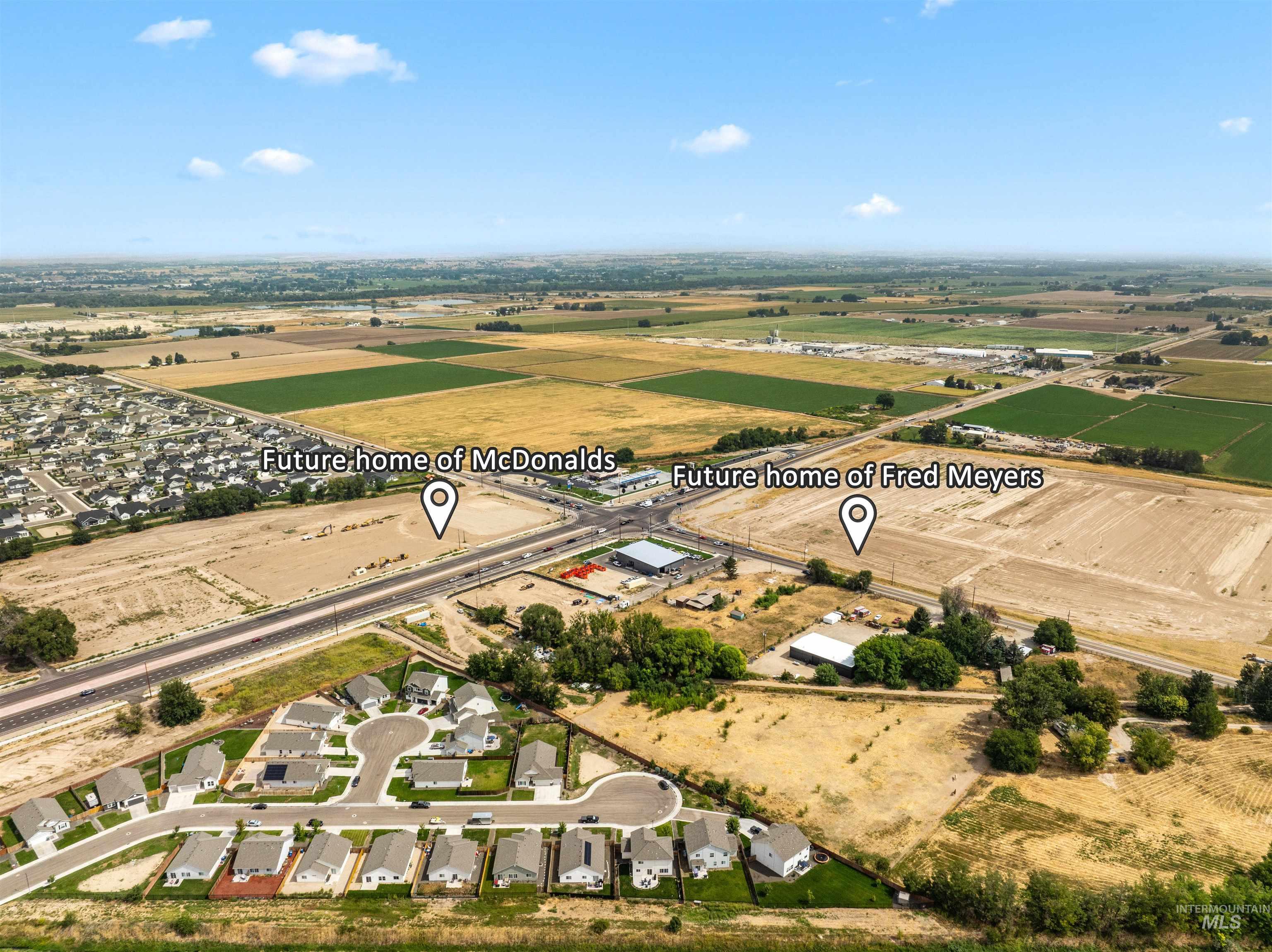 Aerial view of property and surrounding area featuring rural landscape and nearby suburban area