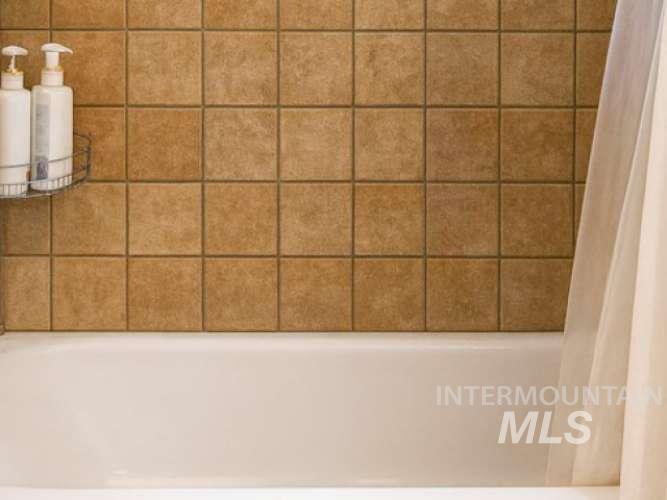 Bathroom view of shower / bathtub combination with curtain