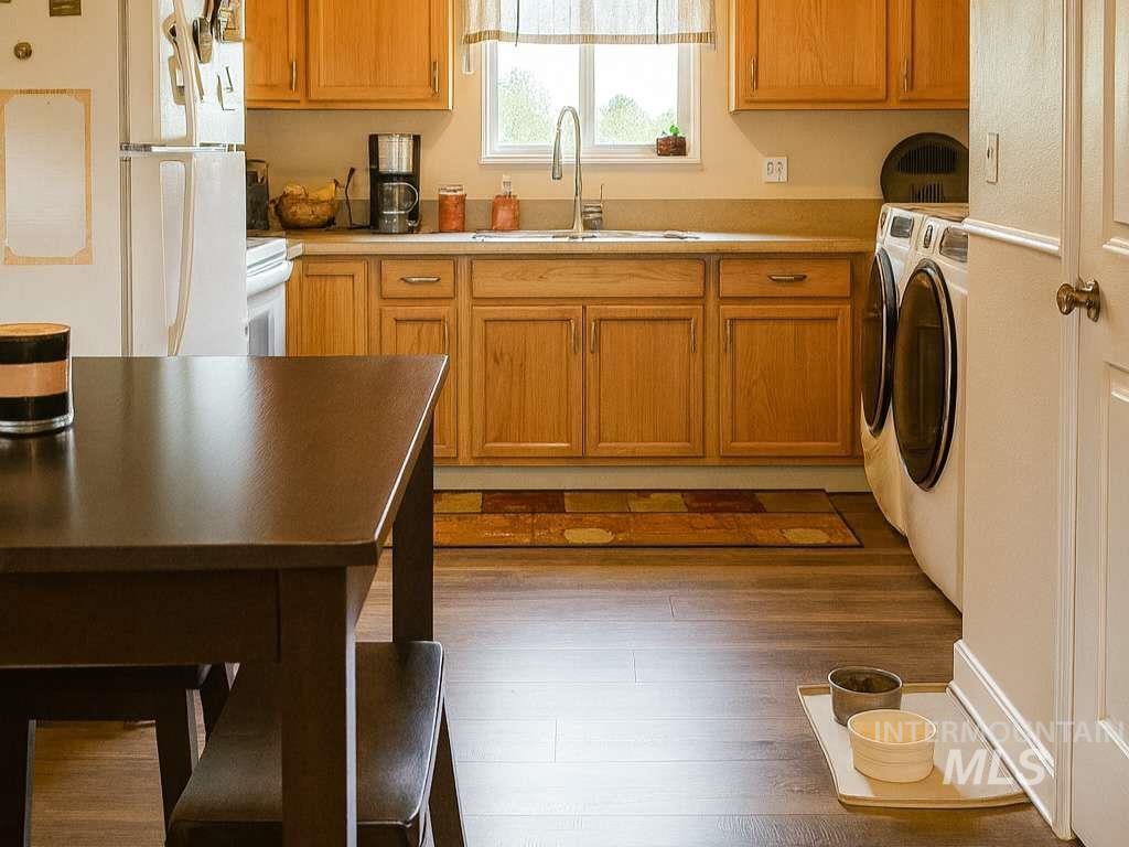 Kitchen featuring white appliances, dark wood-style flooring, light countertops, brown cabinets, and washer and dryer