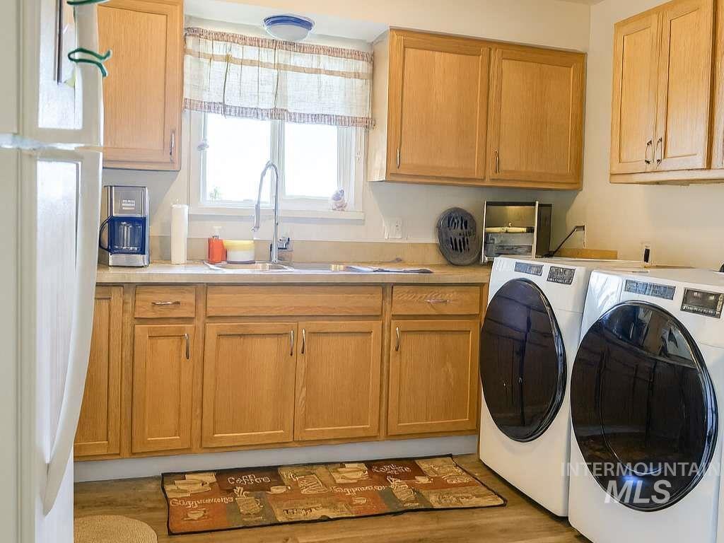 Washroom with washer and clothes dryer, light wood finished floors, and cabinet space
