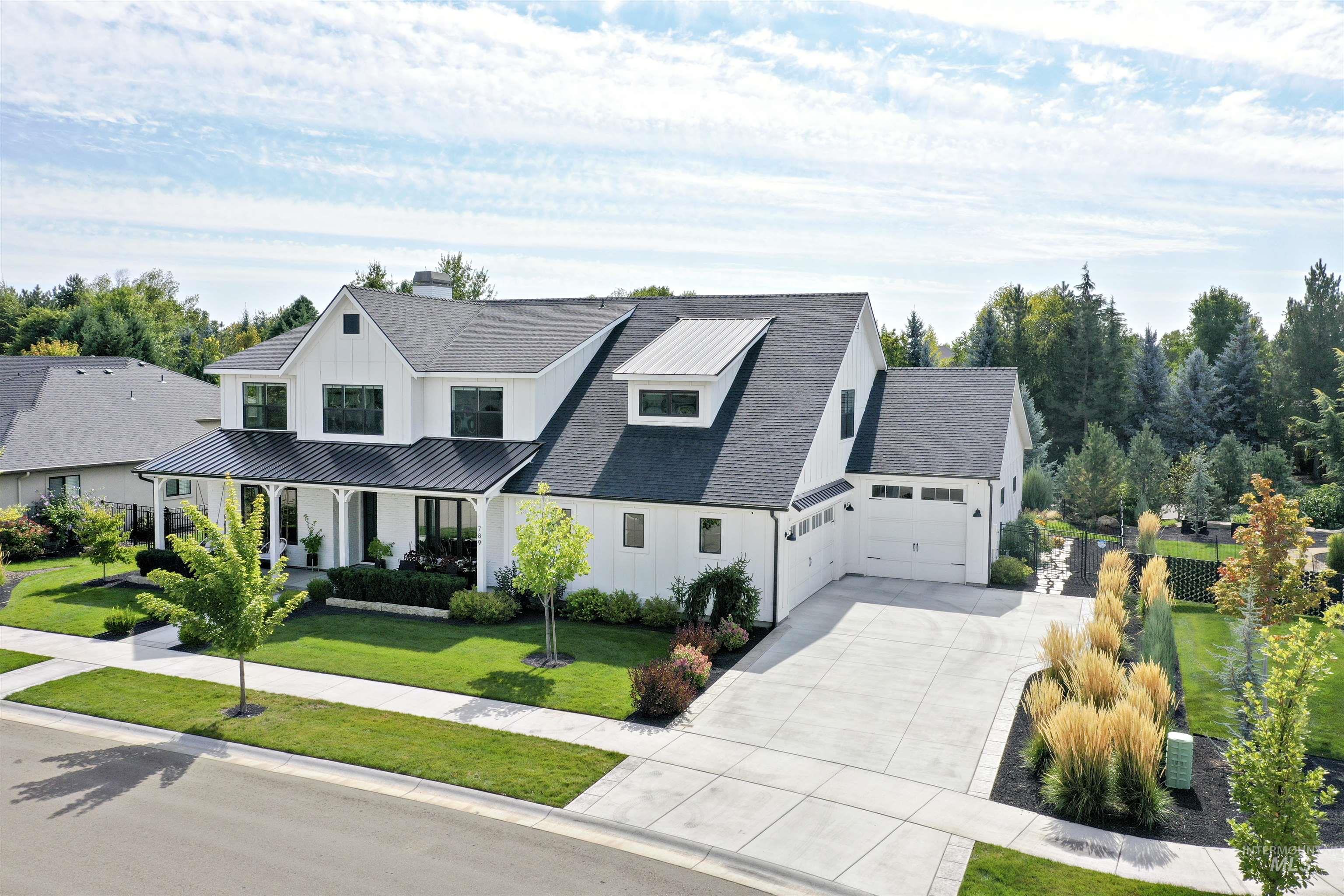 Modern farmhouse style home with board and batten siding, a porch, driveway, a metal roof, and roof with shingles