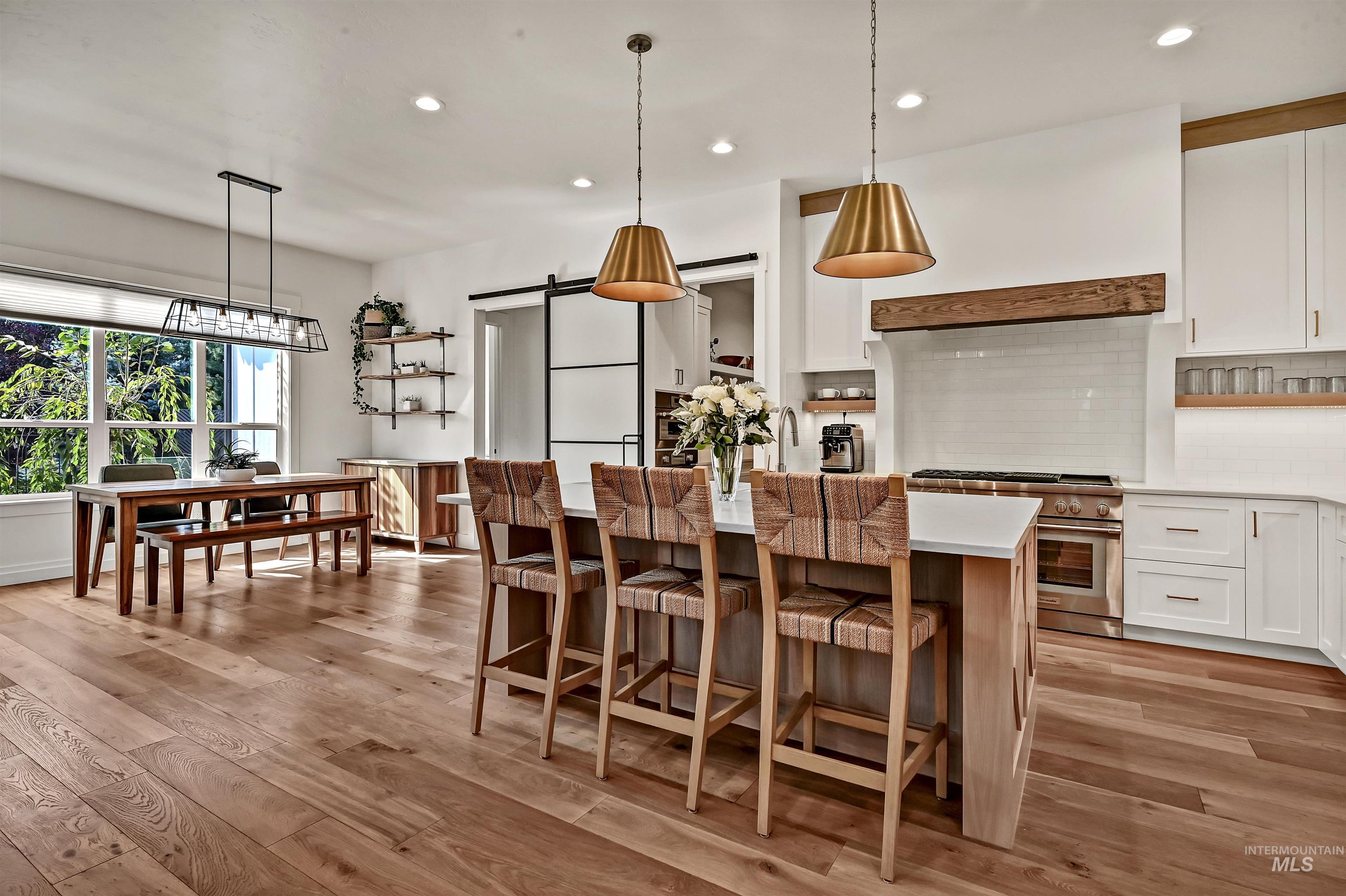 Kitchen with a barn door, white cabinets, backsplash, decorative light fixtures, and recessed lighting