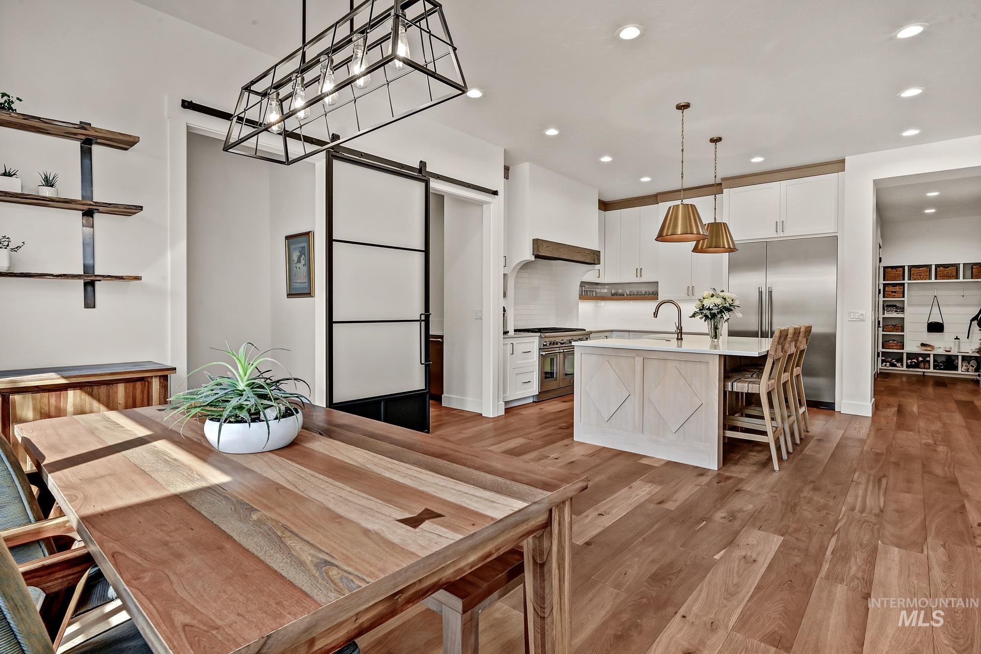 Kitchen featuring a barn door, white cabinetry, high end appliances, an island with sink, and a breakfast bar