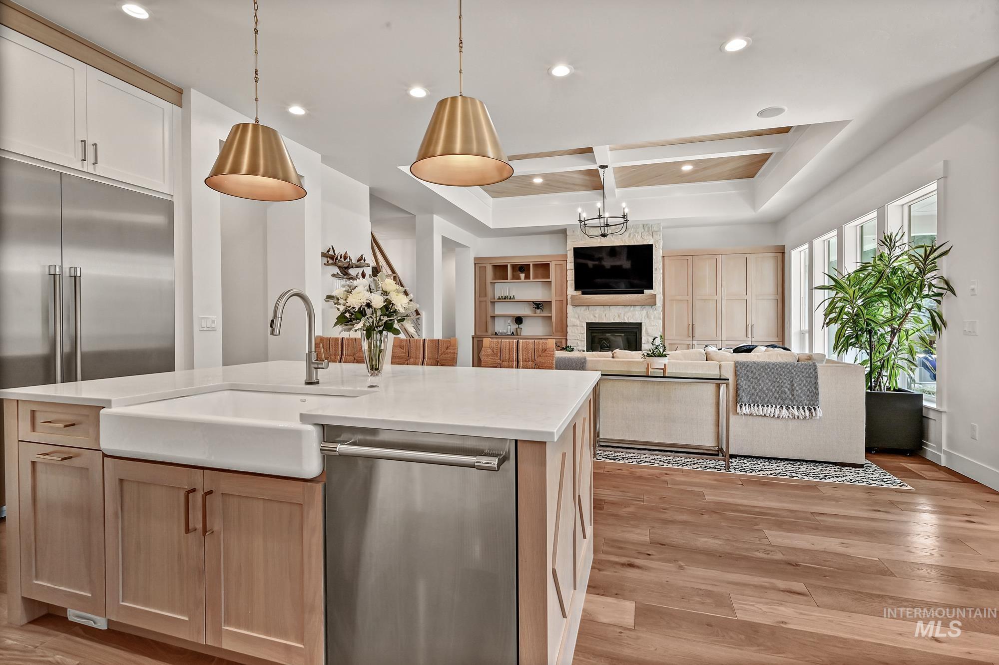 Kitchen with light brown cabinets, dishwasher, light wood finished floors, open floor plan, and hanging light fixtures