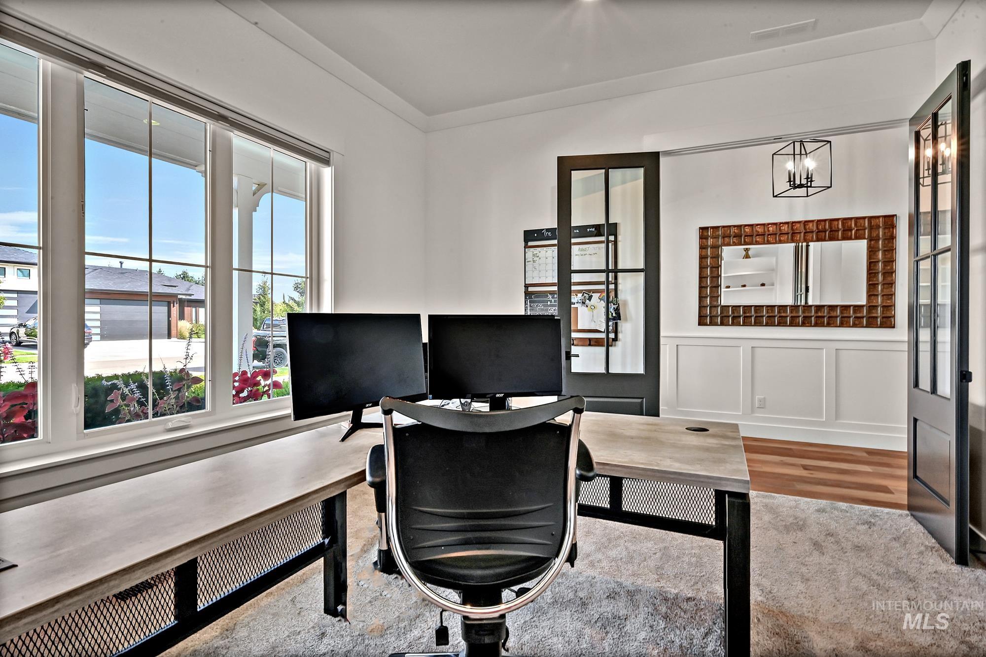 Home office with a wainscoted wall, a decorative wall, ornamental molding, and light wood finished floors