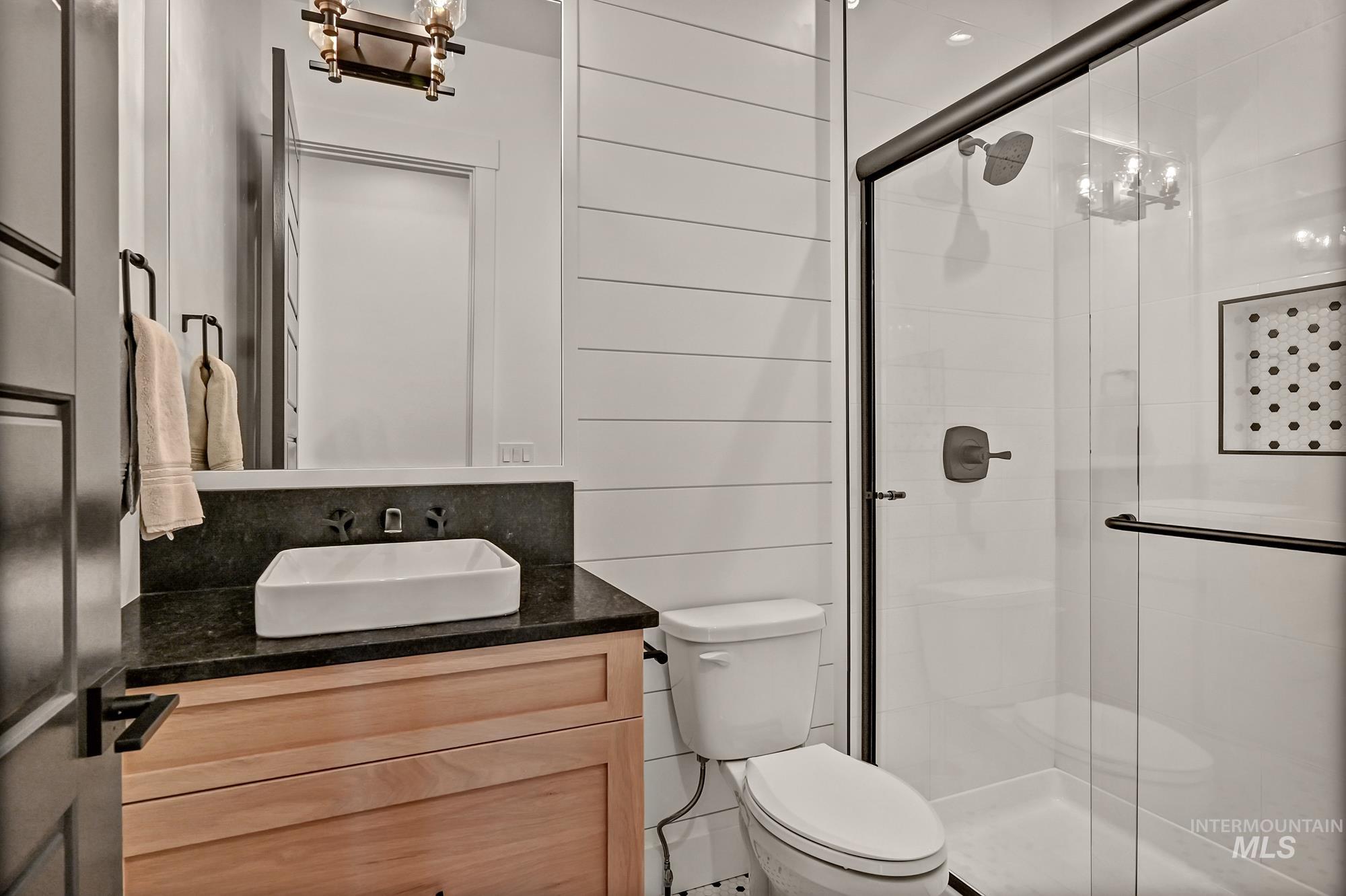 Full bathroom featuring a chandelier, vanity, and a shower stall