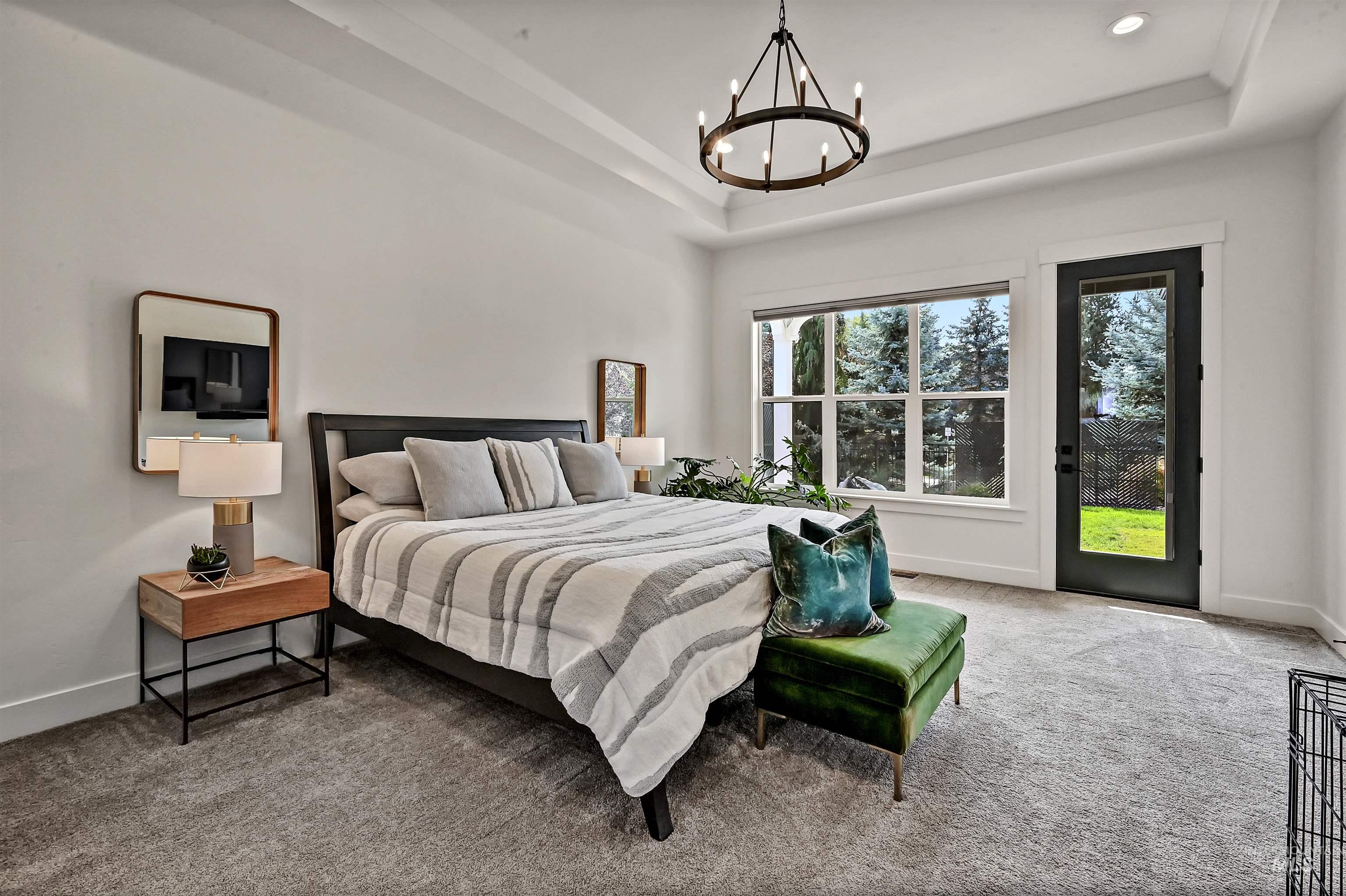 Bedroom featuring carpet floors, a chandelier, a tray ceiling, and access to outside
