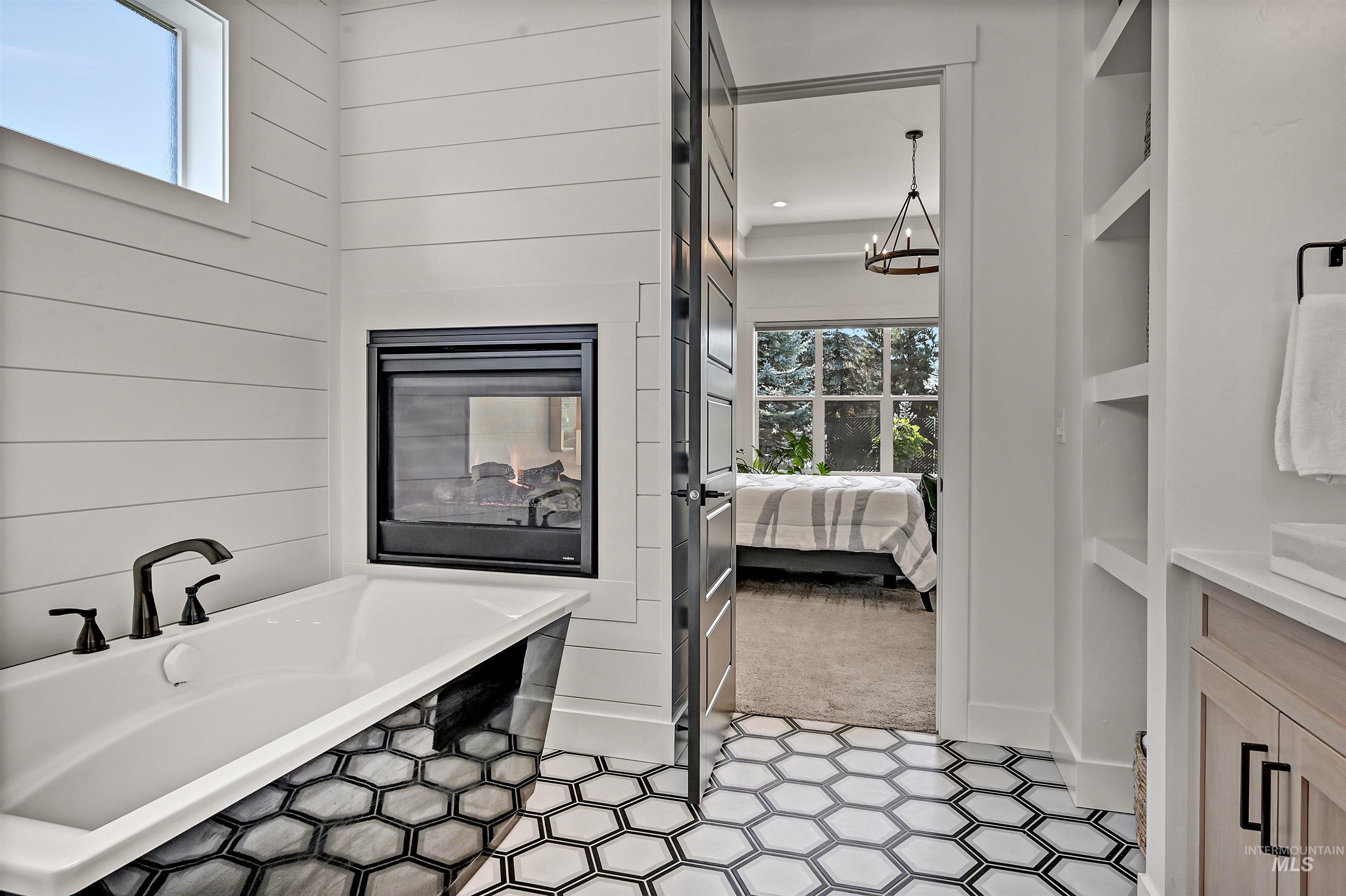Ensuite bathroom with vanity, a freestanding bath, a chandelier, and light tile patterned floors