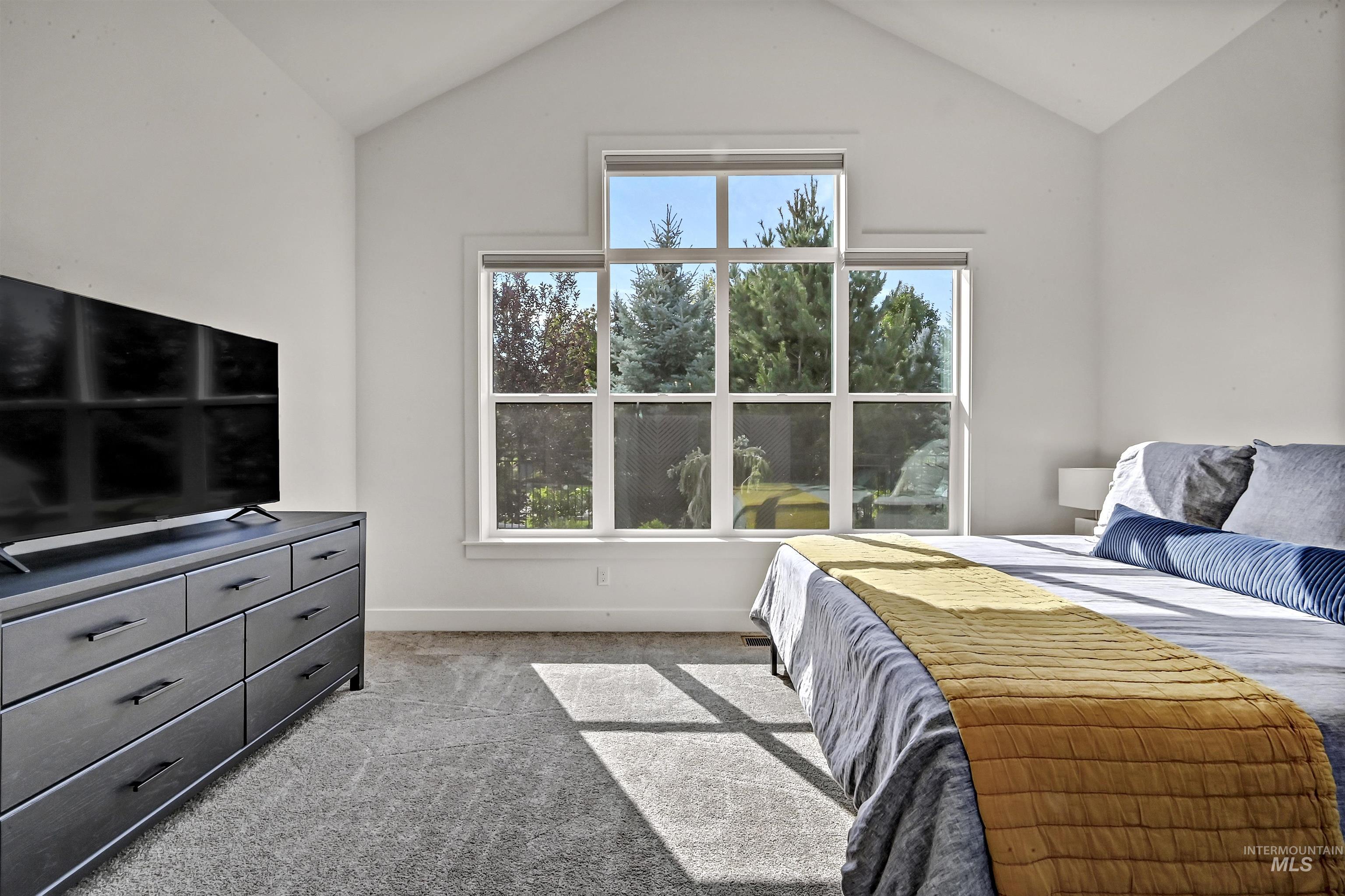 Bedroom with light carpet and vaulted ceiling