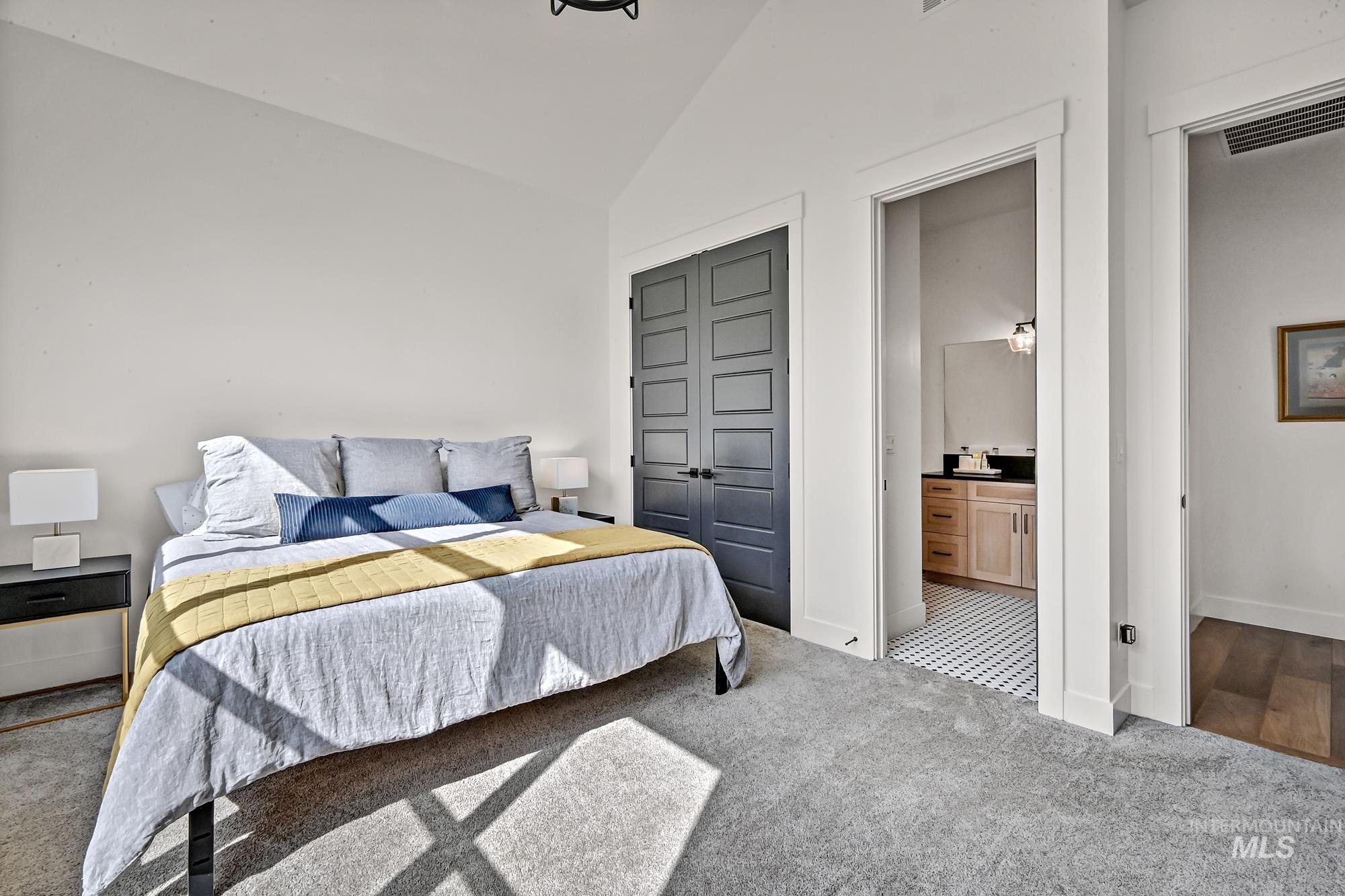 Carpeted bedroom with lofted ceiling, a closet, and connected bathroom