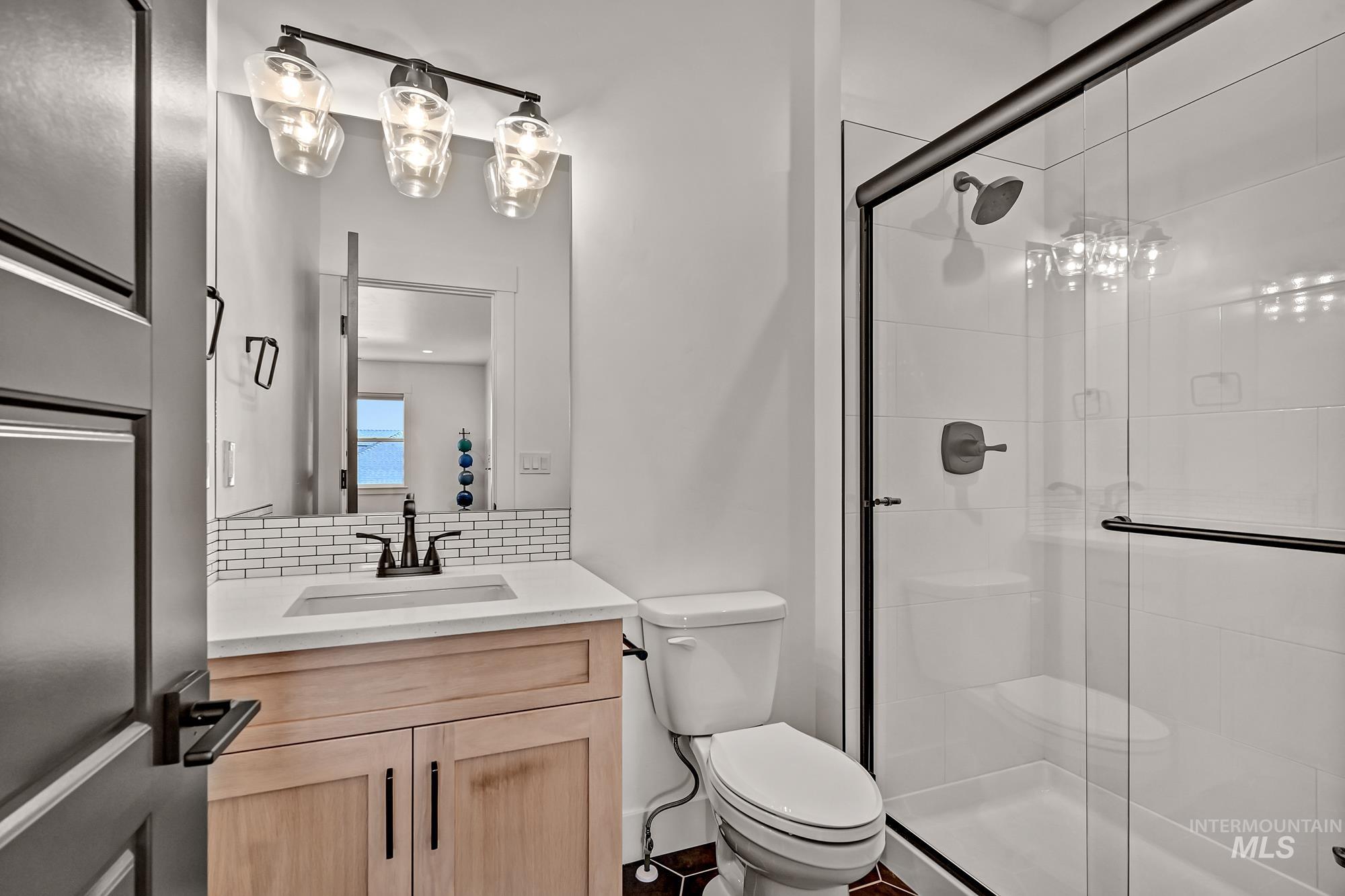 Full bathroom with vanity, backsplash, and a shower stall