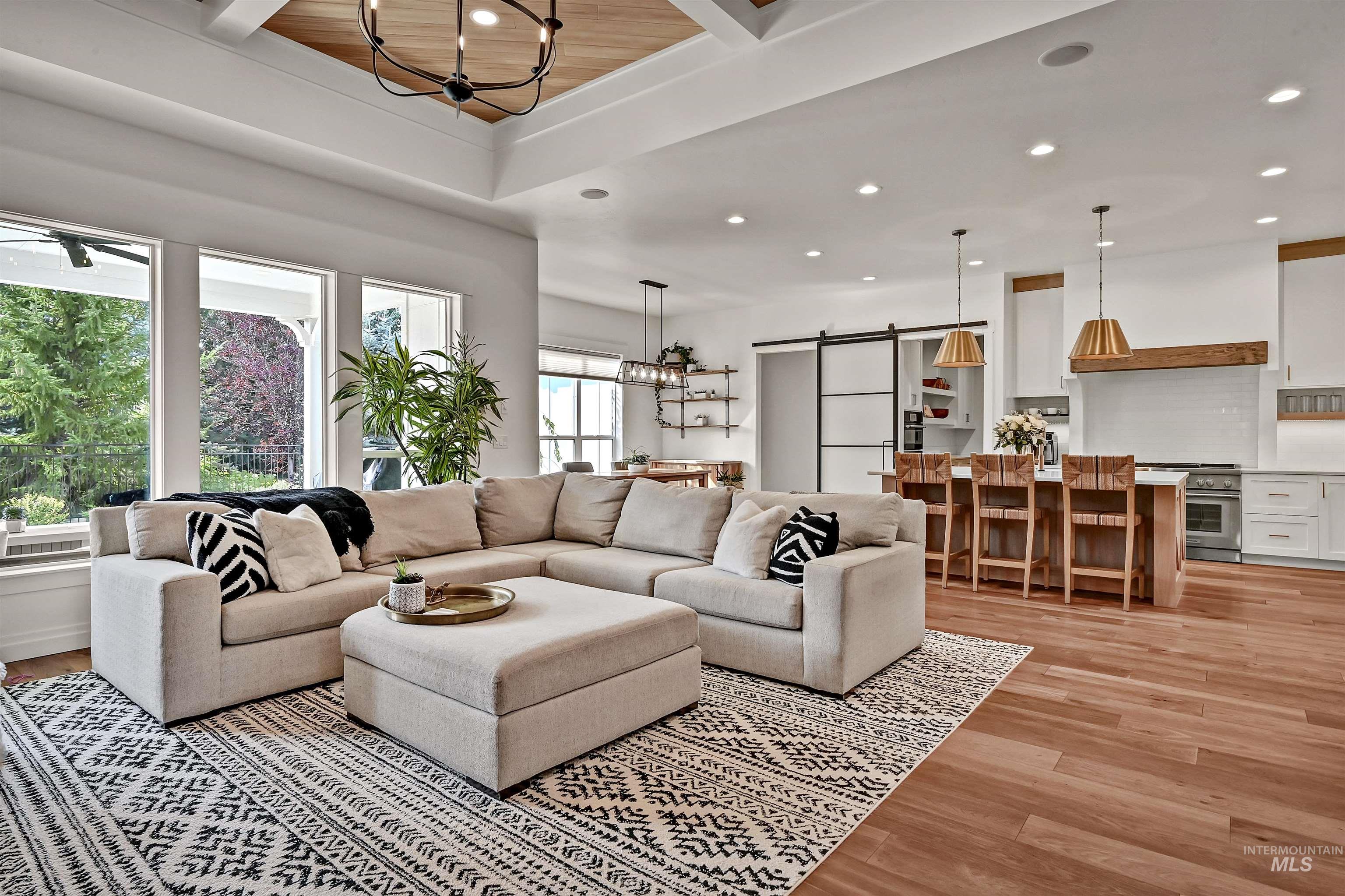 Living area featuring a chandelier, a barn door, light wood-type flooring, recessed lighting, and beam ceiling