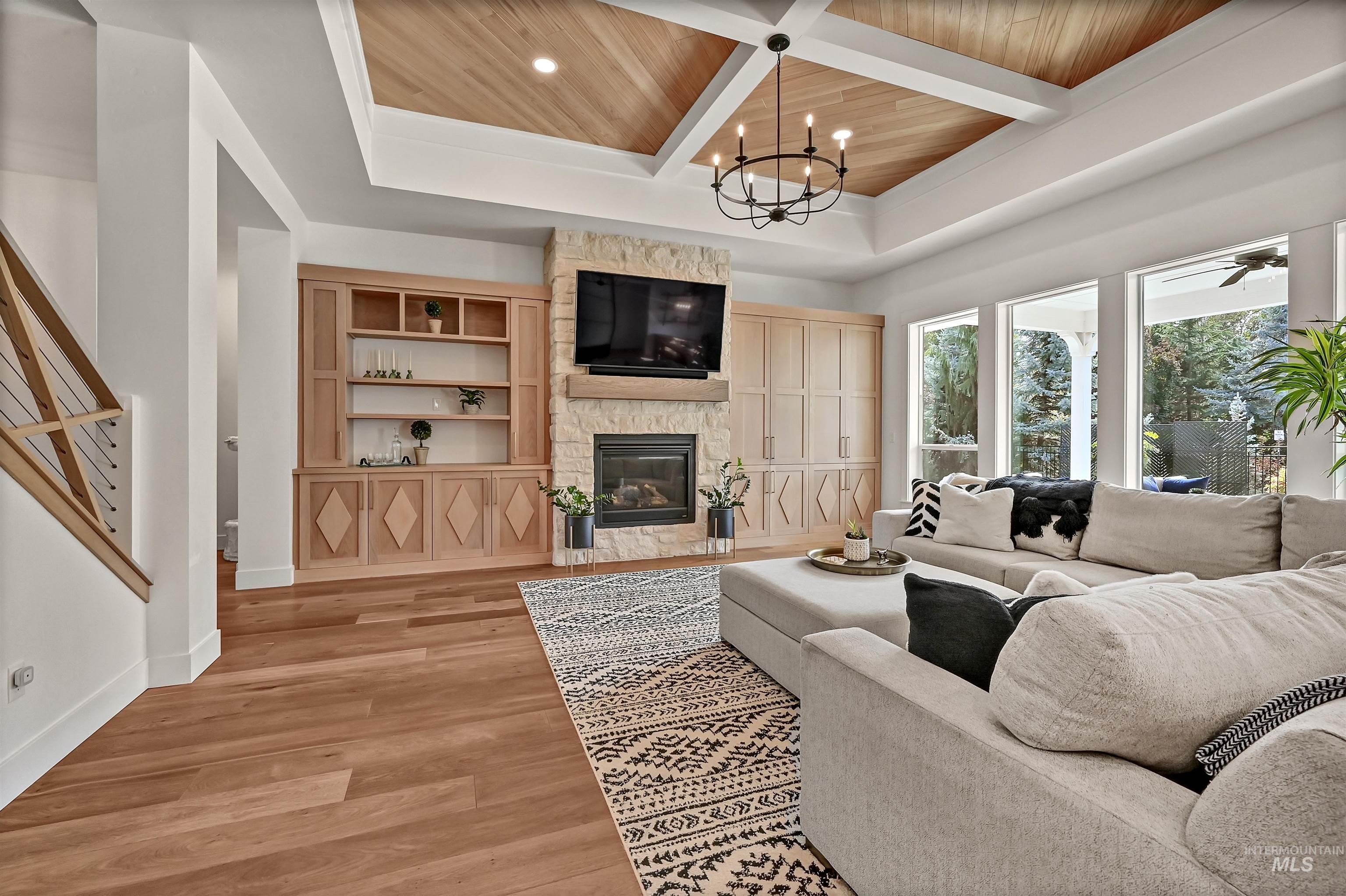 Living room with a fireplace, light wood finished floors, a wooden ceiling with exposed beams, recessed lighting, and stairs