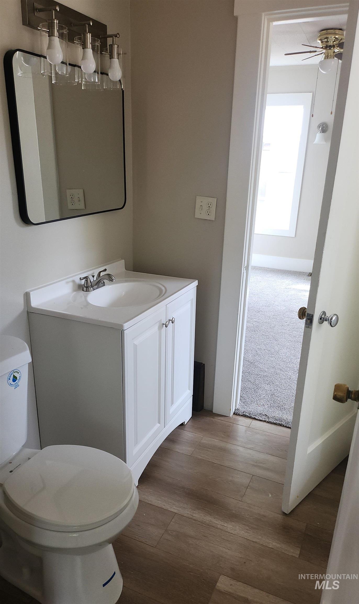 Half bathroom featuring vanity, light wood finished floors, and a ceiling fan