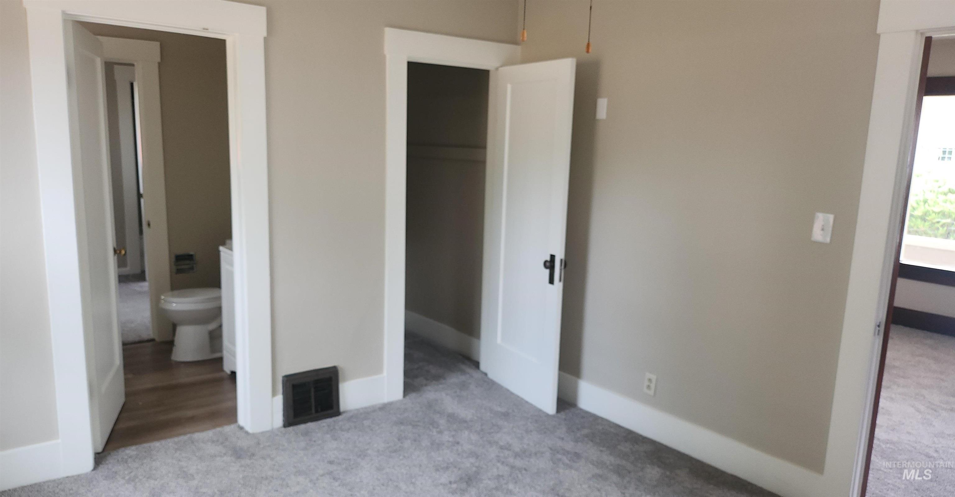 Unfurnished bedroom with light colored carpet, ensuite bath, and a closet
