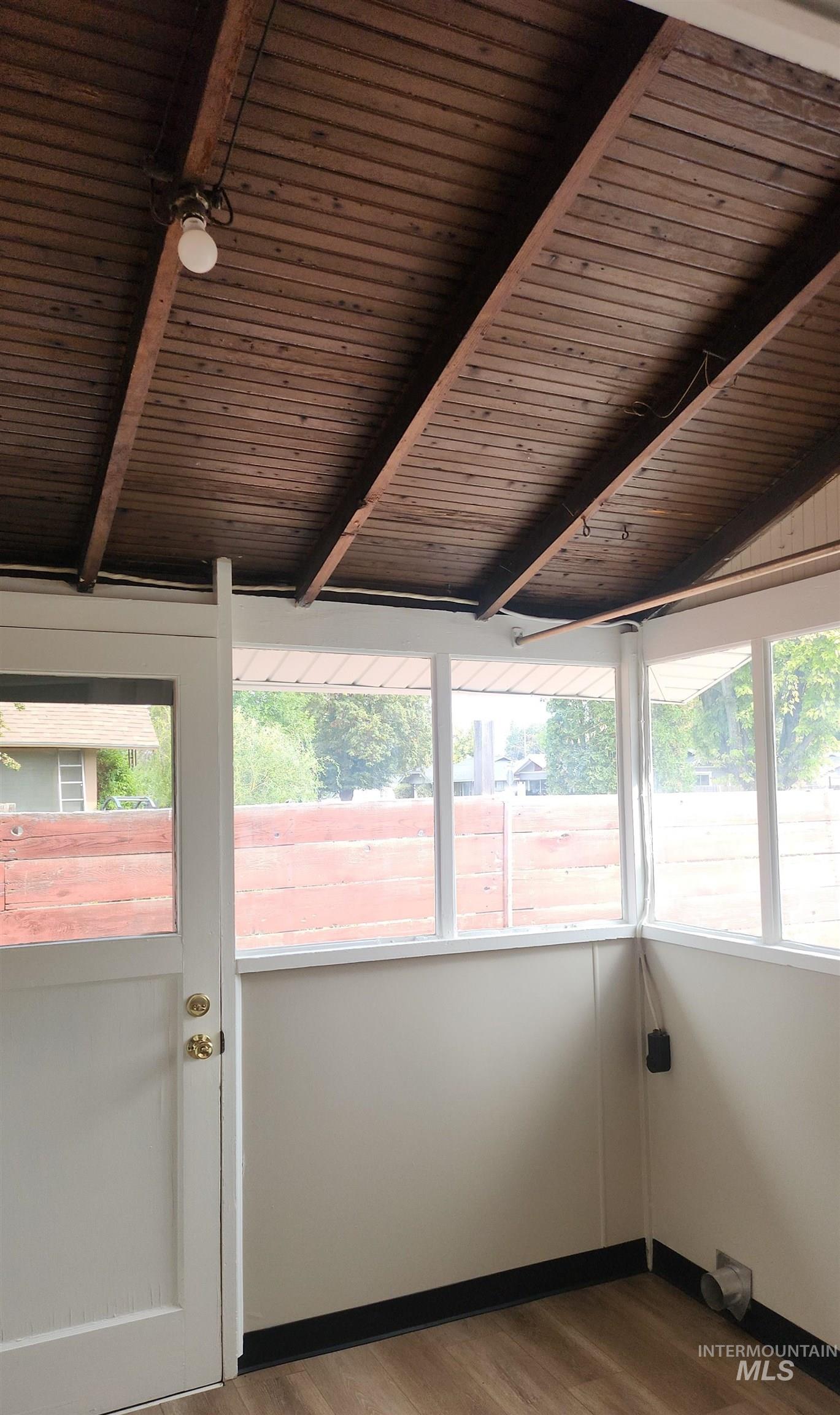 Unfurnished sunroom featuring wood finished floors and baseboards