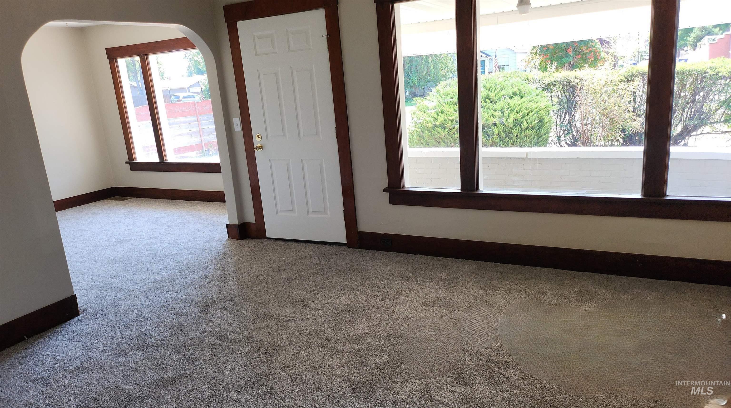 Carpeted empty room featuring arched walkways and baseboards