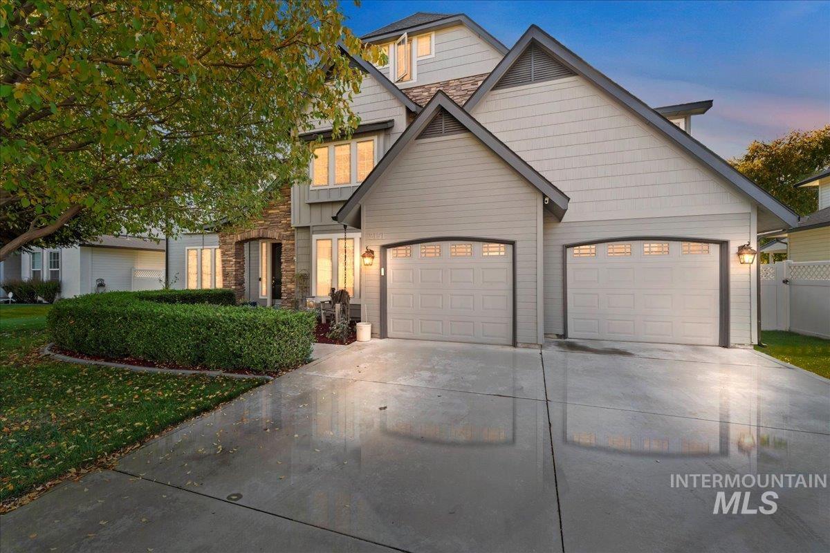 View of front of property with concrete driveway, stone siding, and a garage