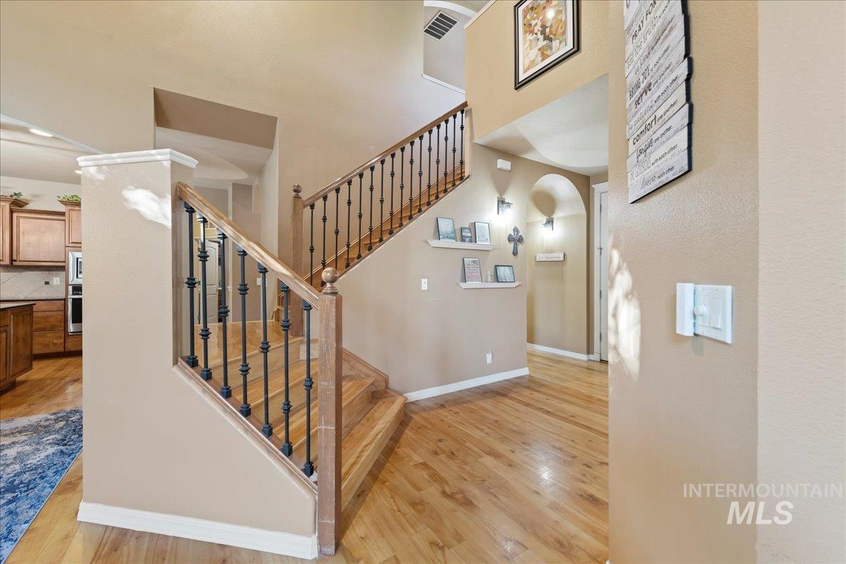 Staircase featuring wood finished floors and arched walkways