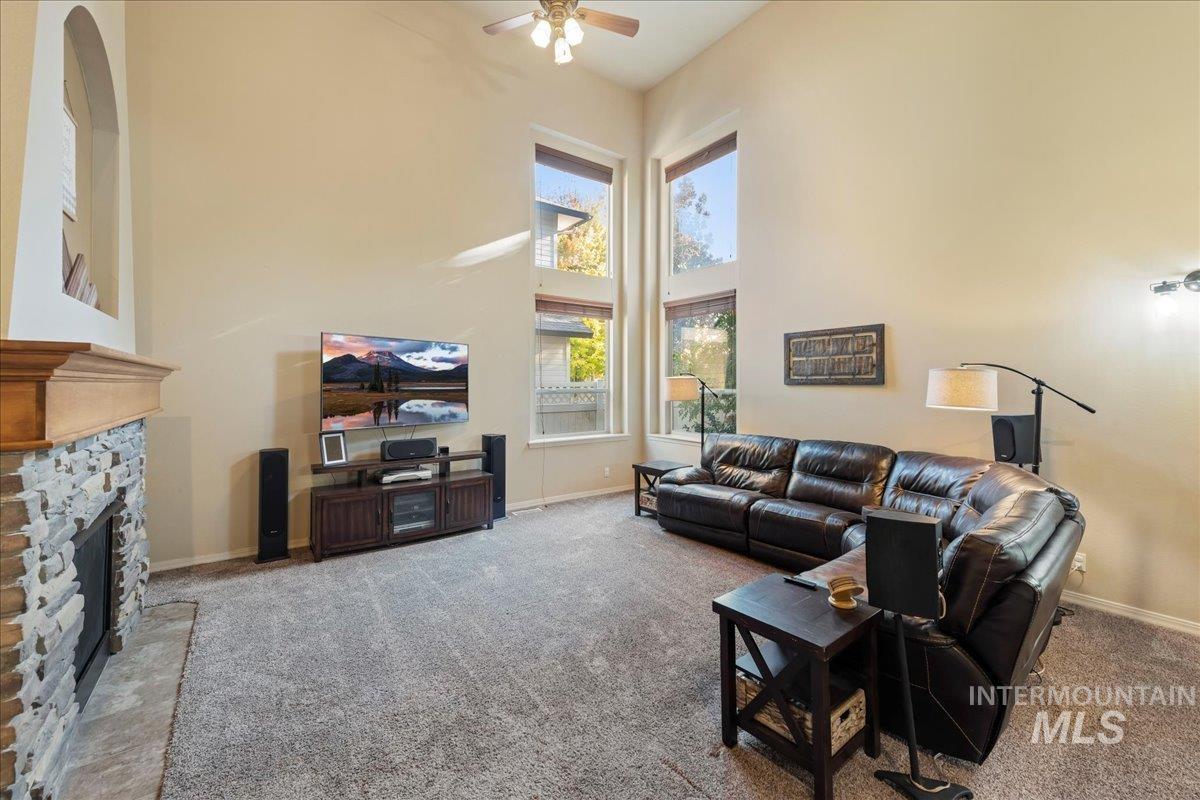 Living area featuring a high ceiling, carpet, a fireplace, and ceiling fan