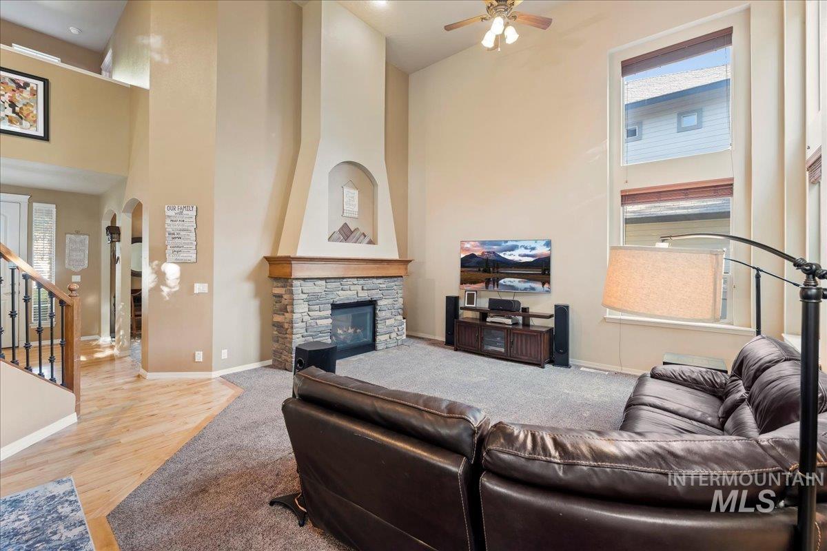 Carpeted living room featuring a high ceiling, stairs, a fireplace, arched walkways, and wood finished floors