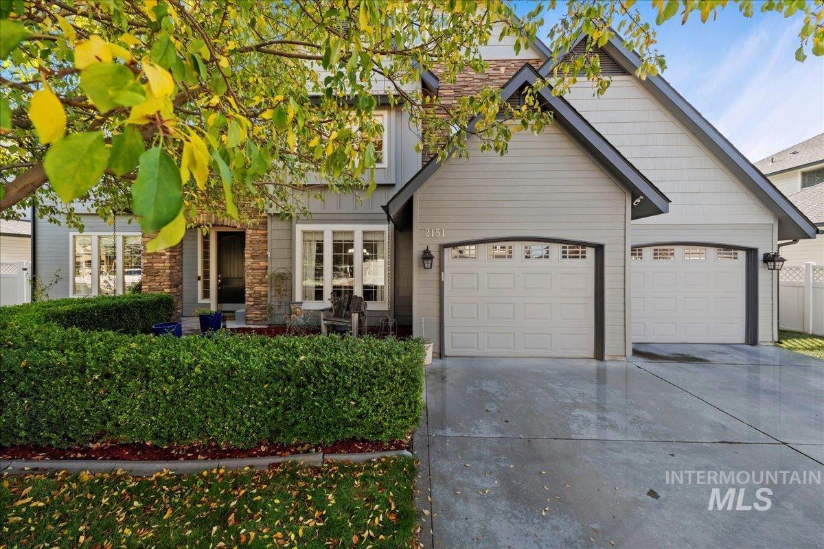 View of front of home featuring concrete driveway, stone siding, and an attached garage