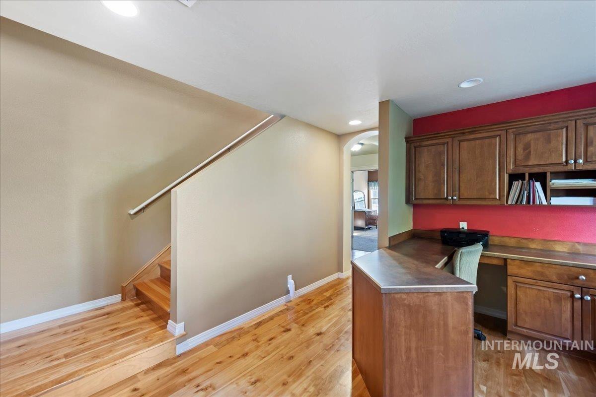 Kitchen with light wood-type flooring, arched walkways, dark countertops, recessed lighting, and a peninsula