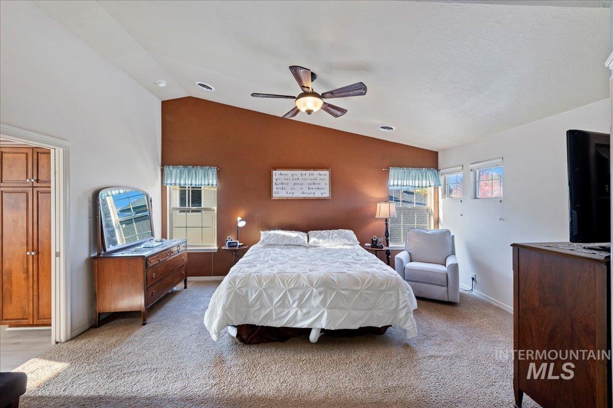 Carpeted bedroom with vaulted ceiling and ceiling fan