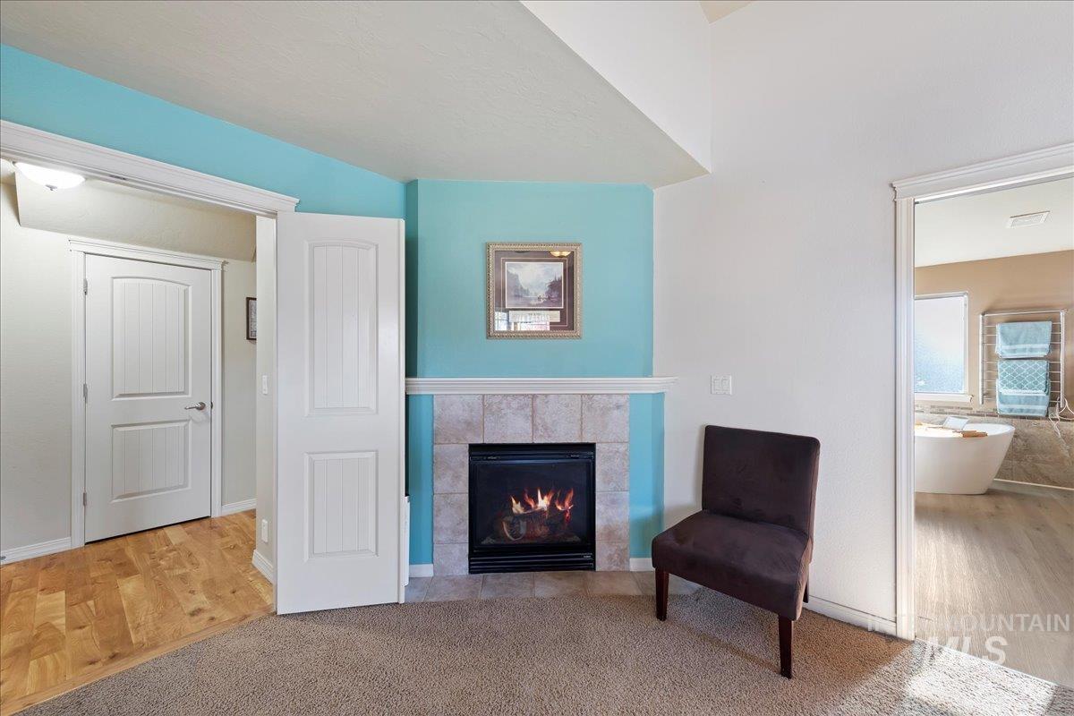 Sitting room with a tile fireplace, wood finished floors, and carpet