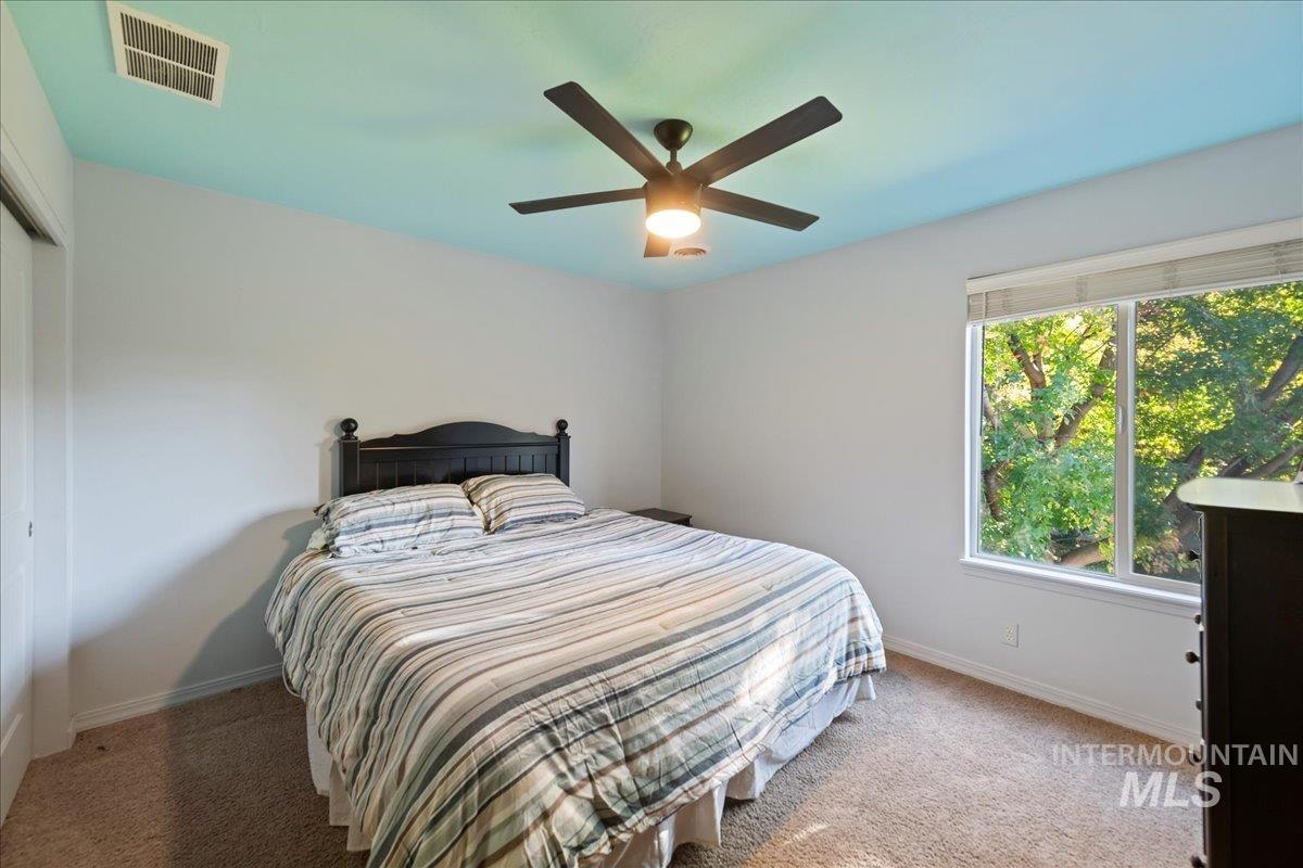 Carpeted bedroom with ceiling fan and a closet