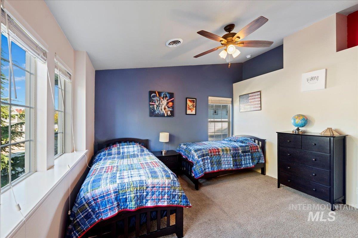 Bedroom with carpet, vaulted ceiling, and a ceiling fan