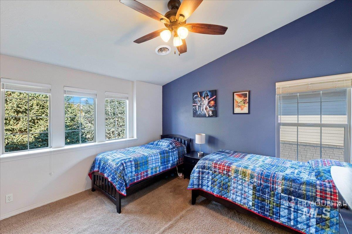 Carpeted bedroom with lofted ceiling and ceiling fan