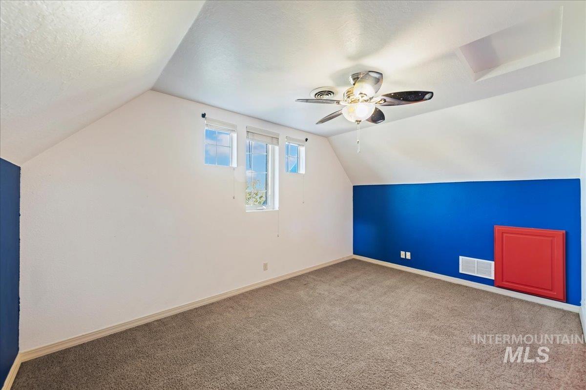 Additional living space featuring vaulted ceiling, carpet flooring, a ceiling fan, and a textured ceiling