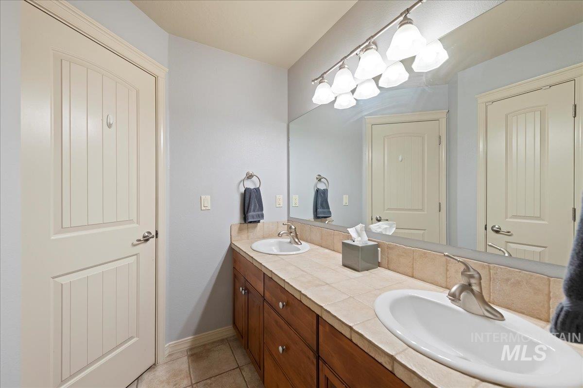 Full bathroom with double vanity and light tile patterned flooring