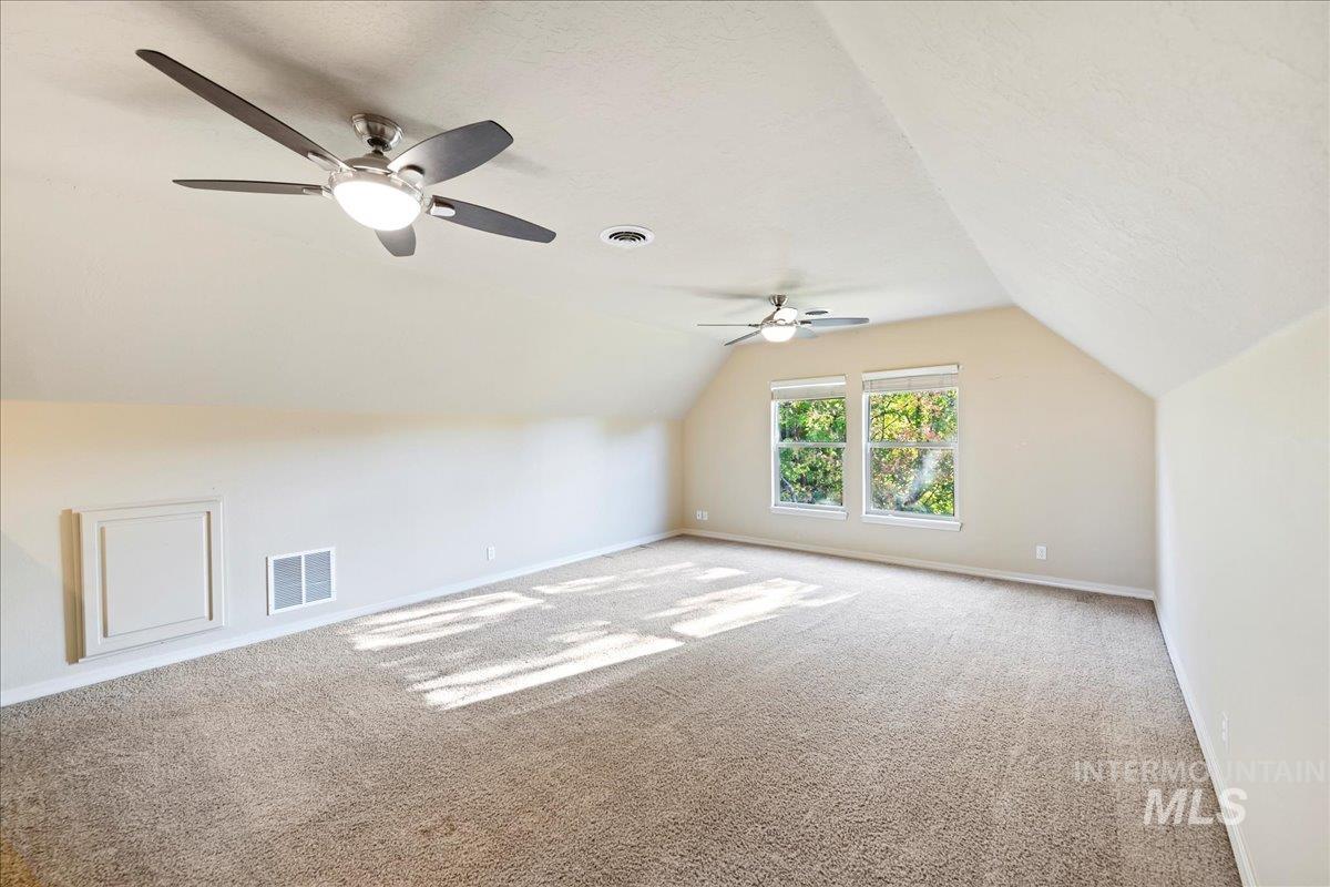 Bonus room featuring vaulted ceiling, carpet flooring, and a textured ceiling