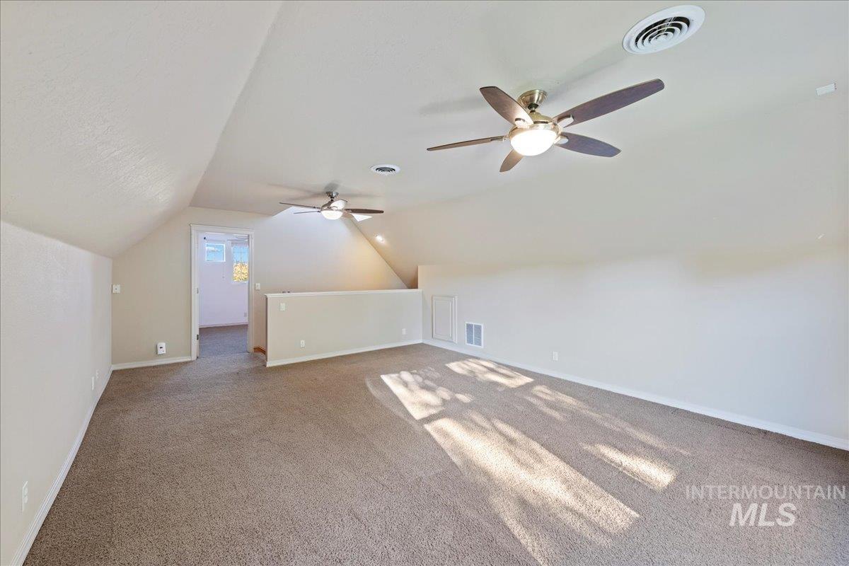 Additional living space featuring carpet flooring, lofted ceiling, and a ceiling fan
