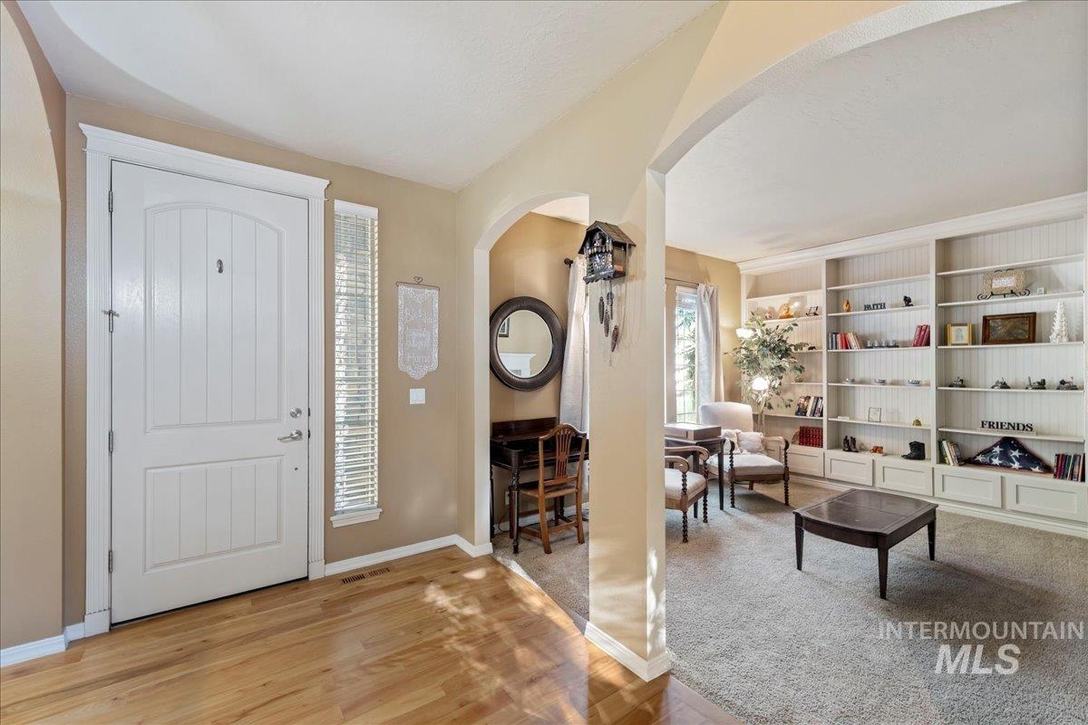 Foyer with arched walkways and light wood-style floors
