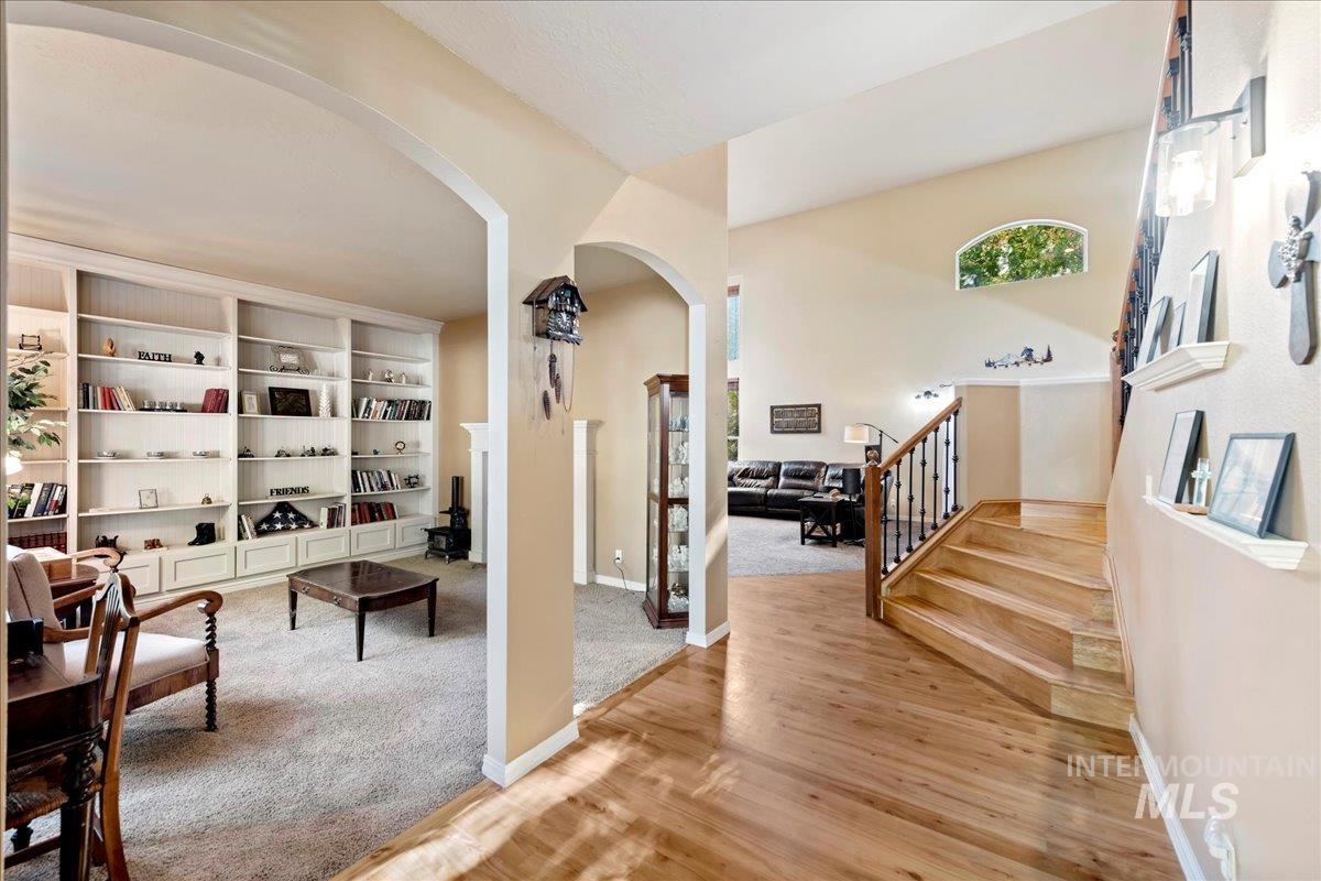 Hall featuring arched walkways, stairway, light wood finished floors, and light colored carpet