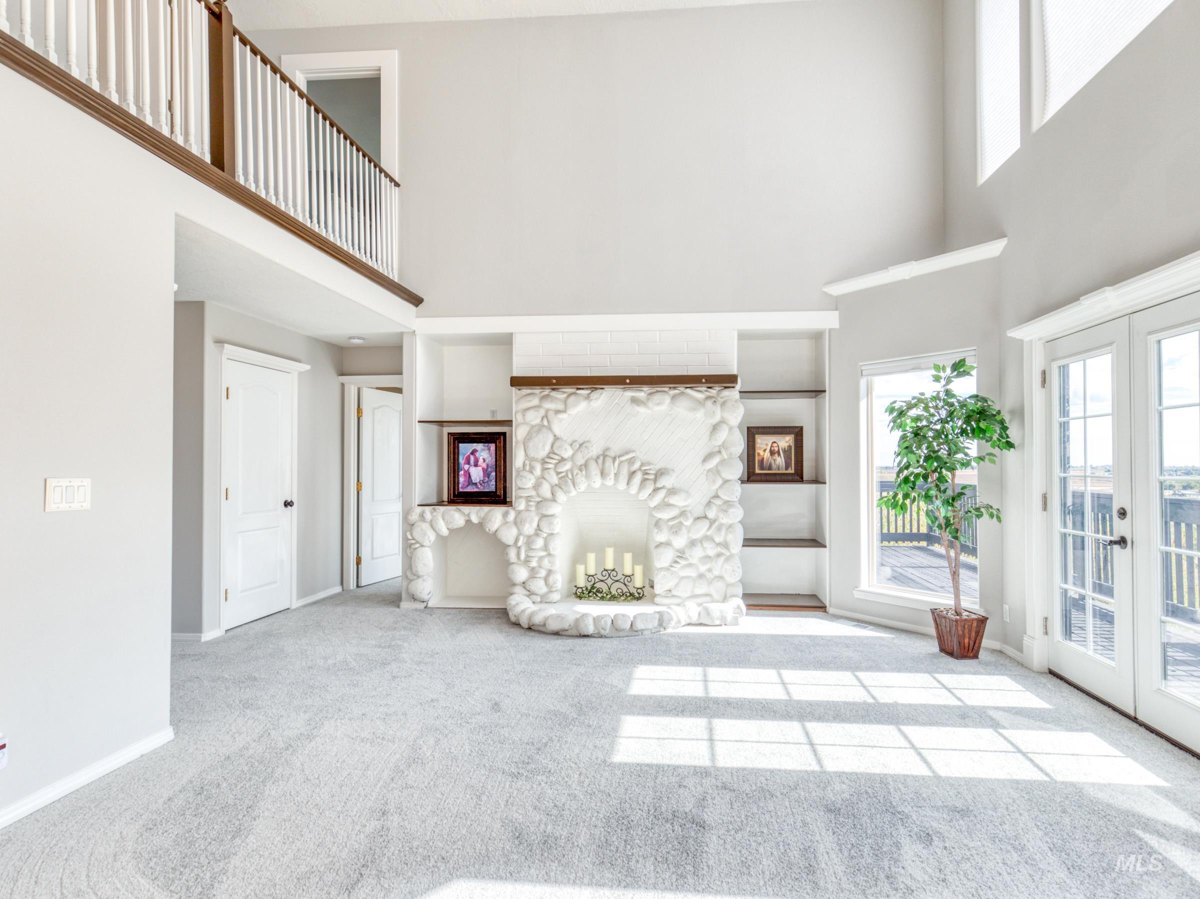 Unfurnished living room with a high ceiling, carpet flooring, french doors, and a fireplace