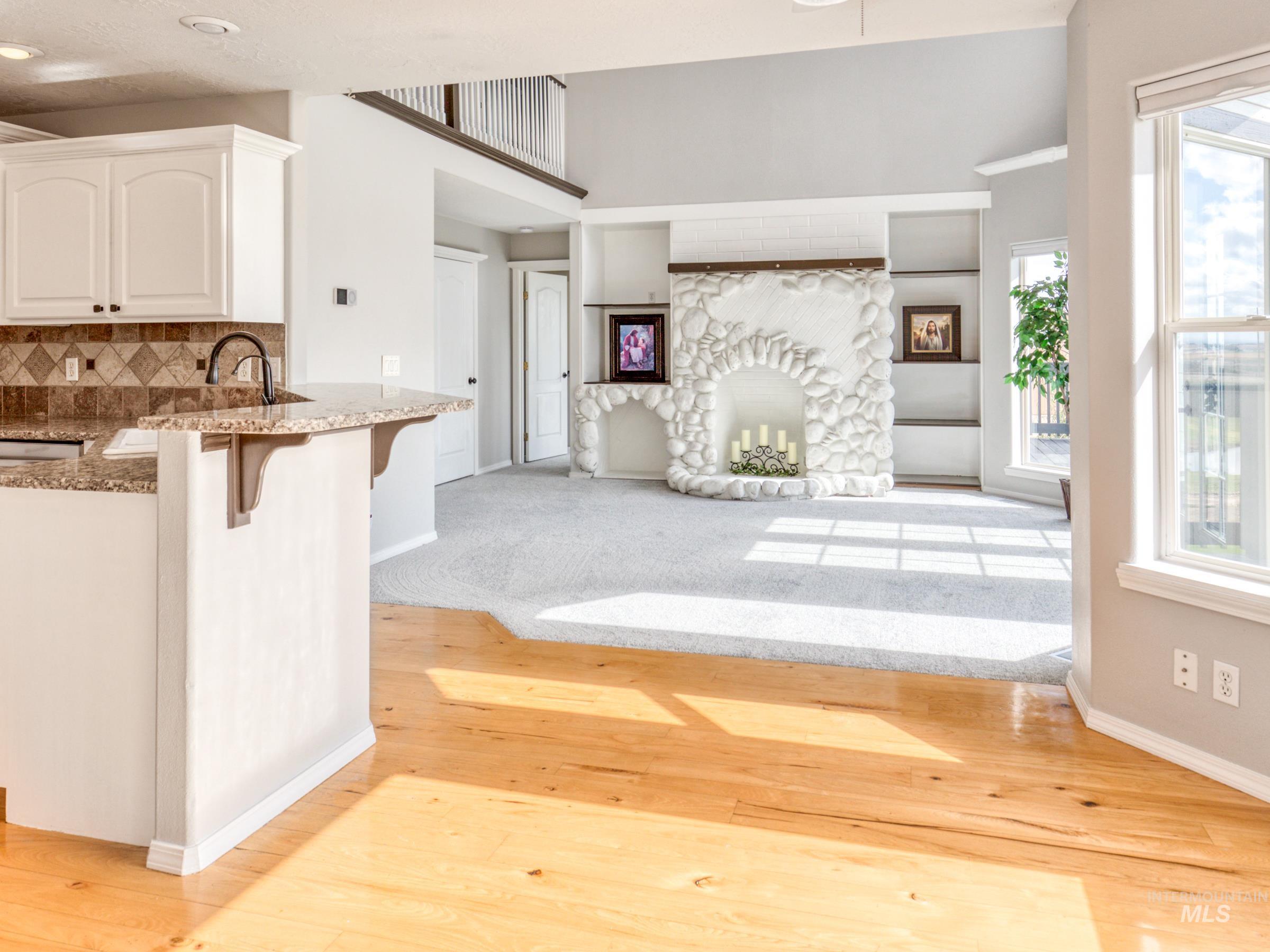 Kitchen featuring a breakfast bar area, light wood-style flooring, open floor plan, white cabinetry, and a fireplace
