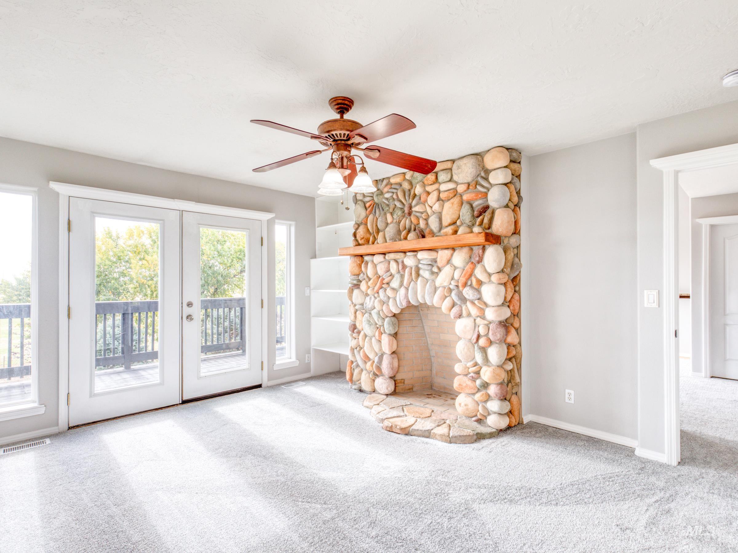 Unfurnished master featuring light carpet, a fireplace, and a ceiling fan
