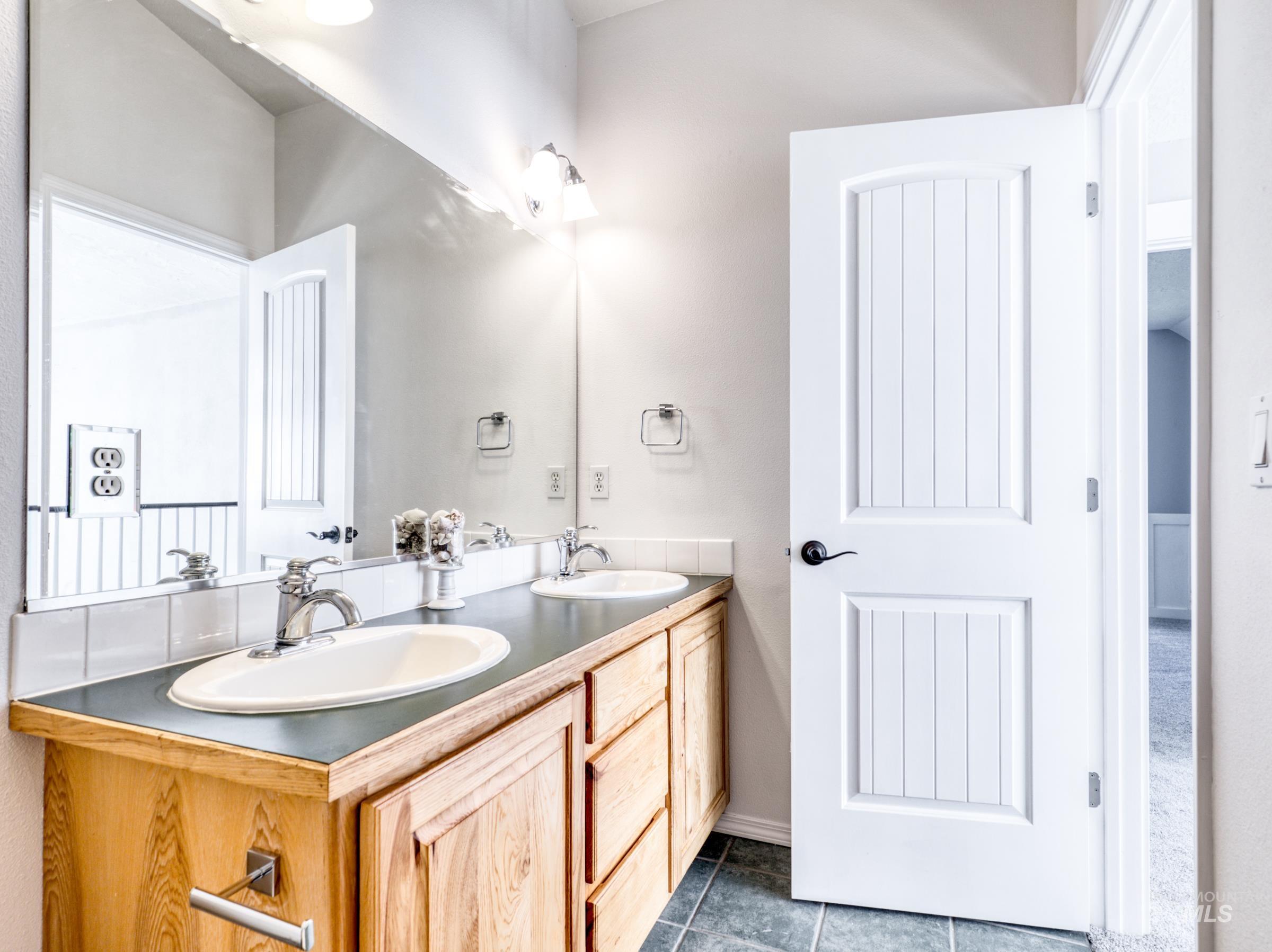 Full bathroom with dark tile patterned flooring and double vanity