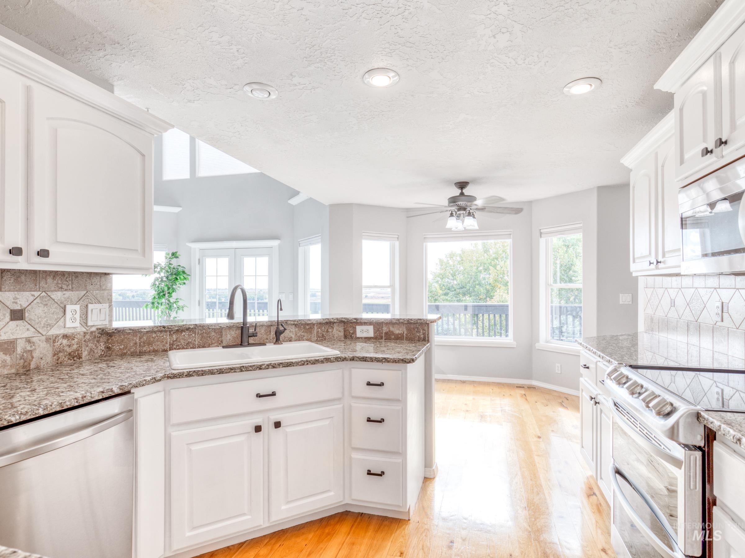 Kitchen featuring tasteful backsplash, stainless steel appliances, white cabinetry, healthy amount of natural light, and recessed lighting