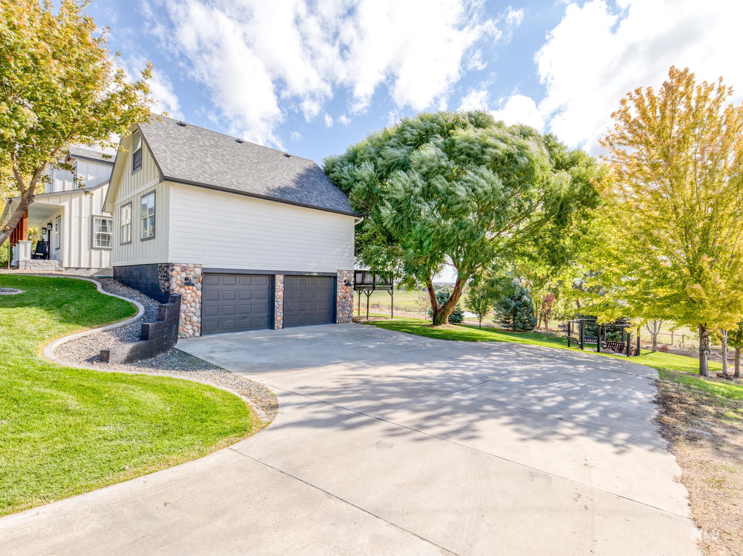 View of home's exterior featuring a lawn, concrete driveway, an attached garage, stone siding, and roof with shingles