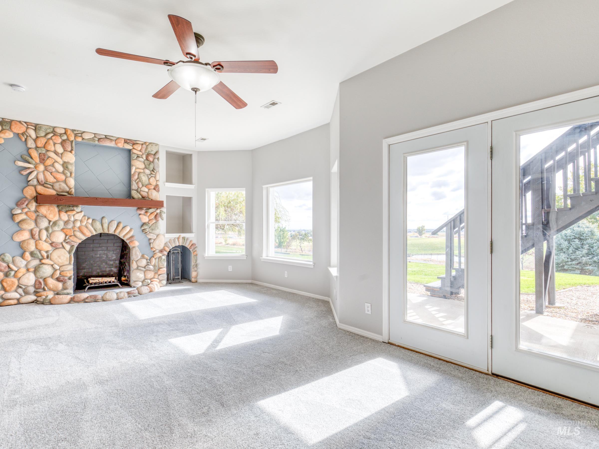 Unfurnished living room with carpet, a fireplace, a ceiling fan, and built in shelves