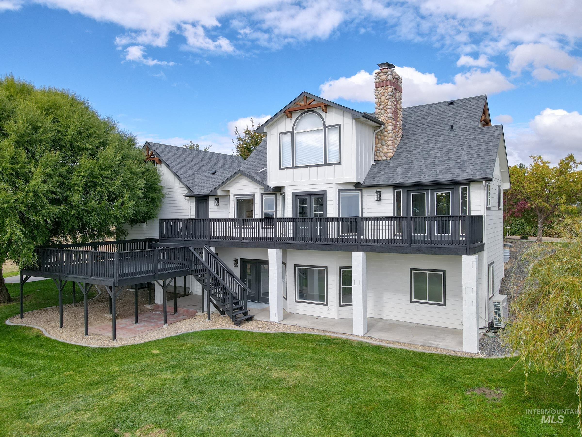 Rear view of house with a patio area, a deck, a shingled roof, and a yard