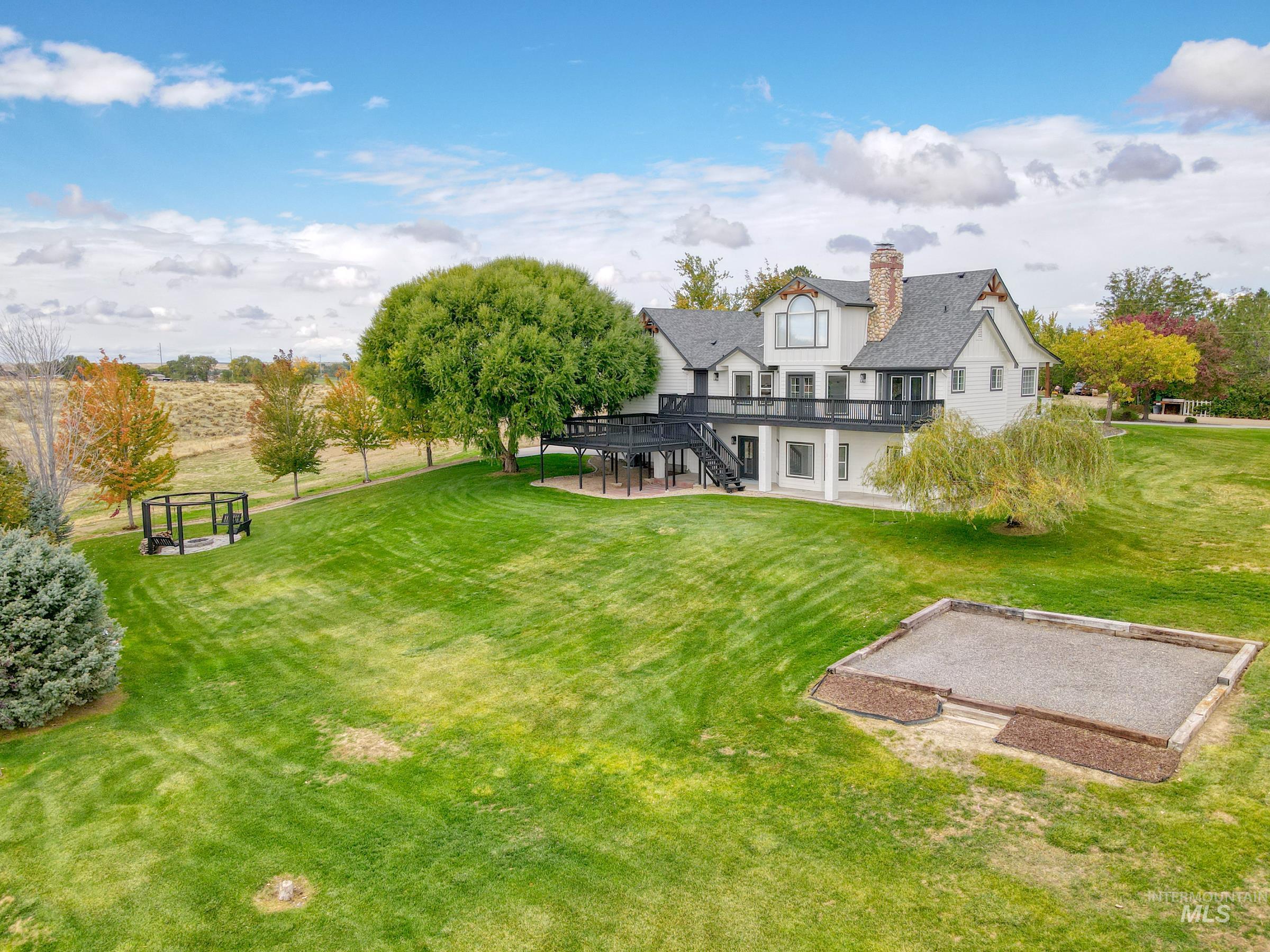 View of grassy yard featuring a patio, stairs, a garden, and a wooden deck