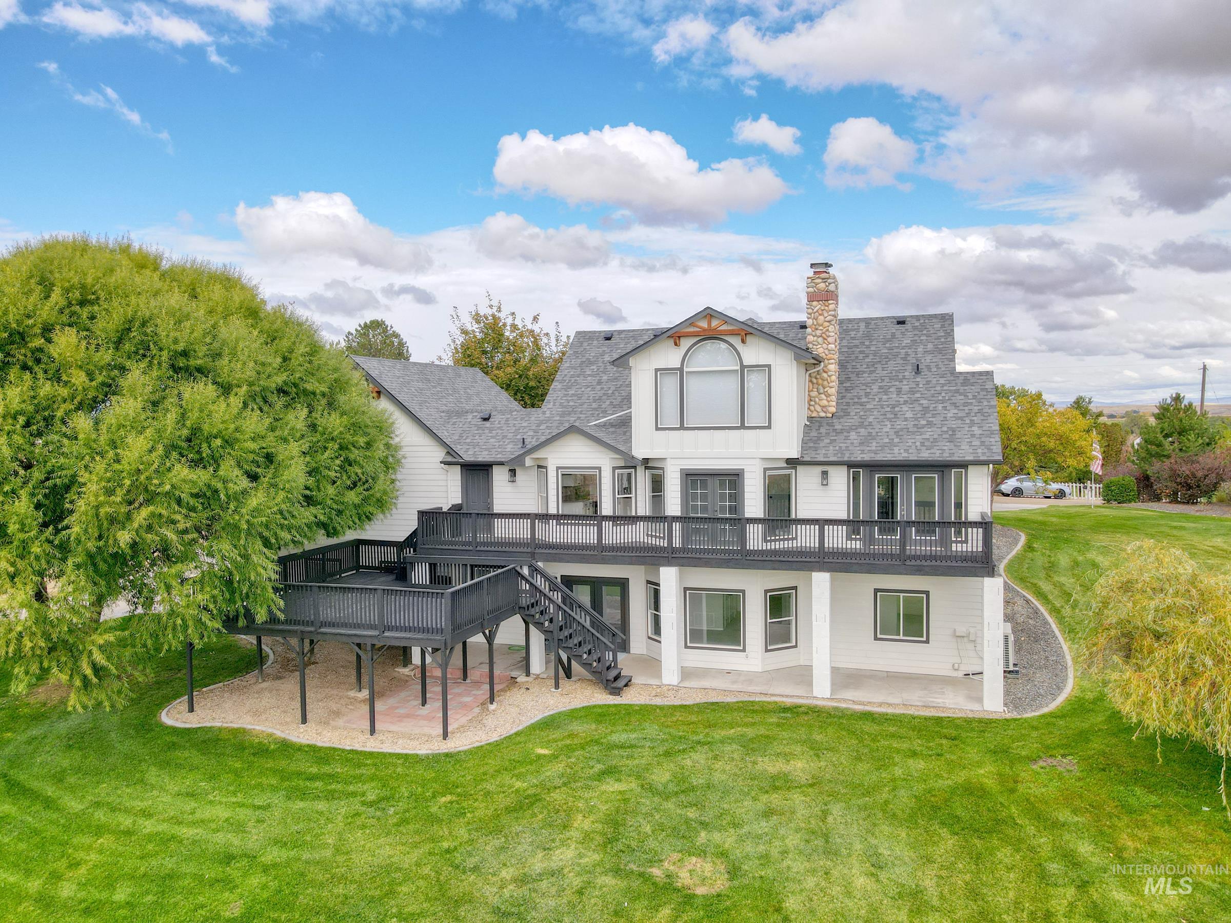 Back of house featuring a patio, a wooden deck, a lawn, and stairway