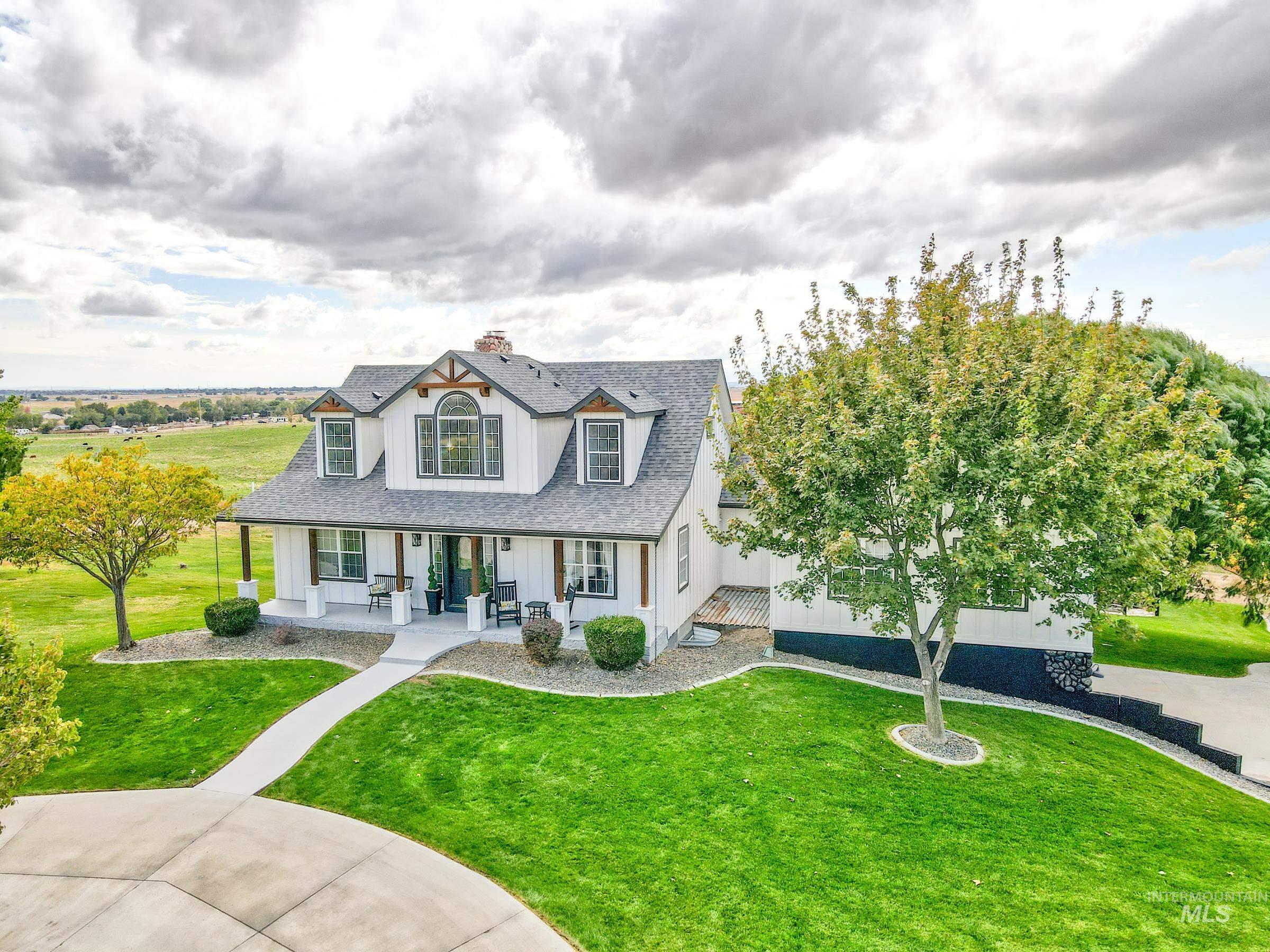 View of front of property with covered porch, a front lawn, a shingled roof, a chimney, and board and batten siding